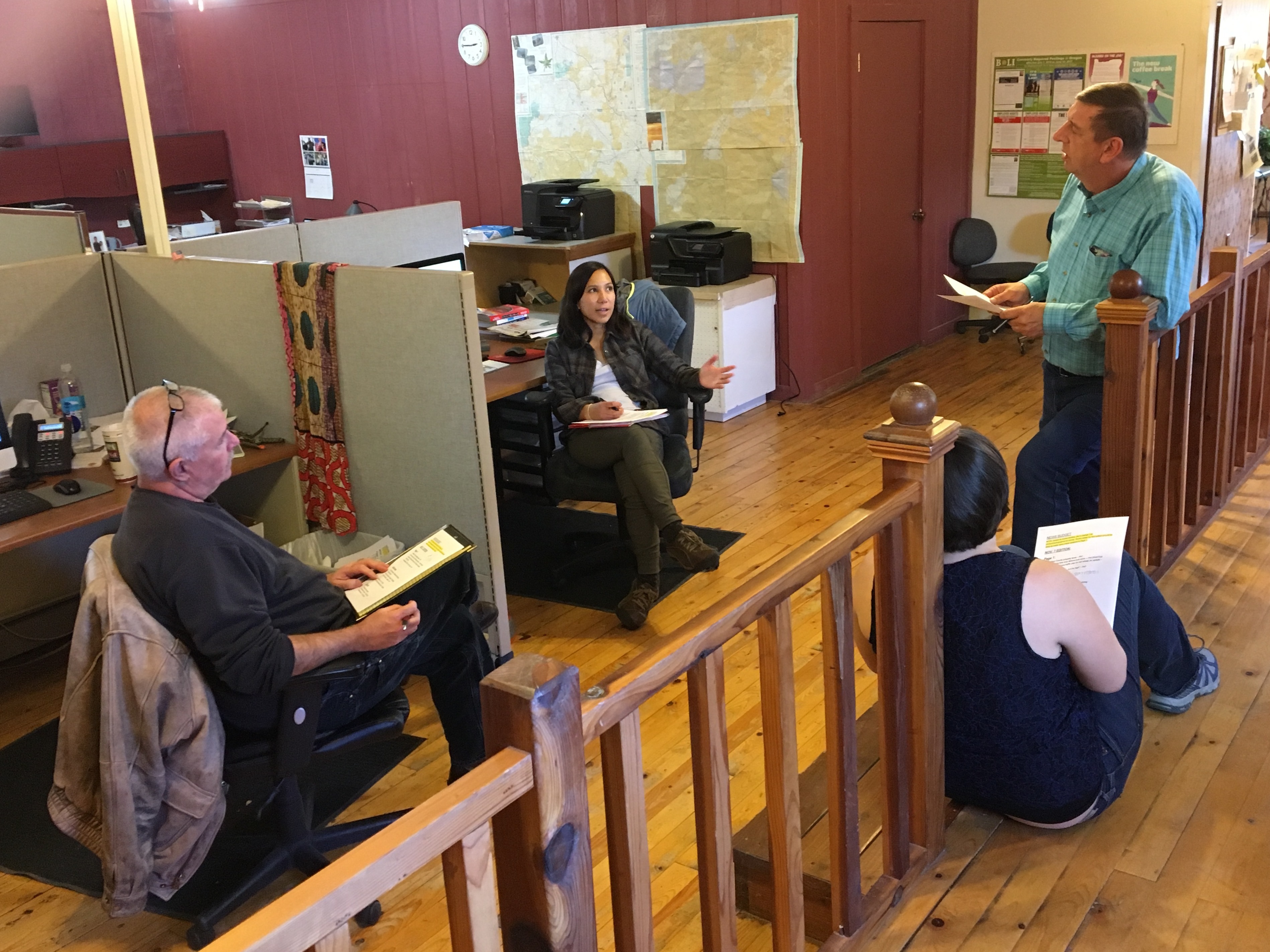 <em>Malheur Enterprise</em> reporters Pat Caldwell (from left) and Kristine de Leon; Les Zaitz, editor and publisher; and, sitting on the floor, reporter Jayme Fraser meet to talk about assignments. (NPR)
