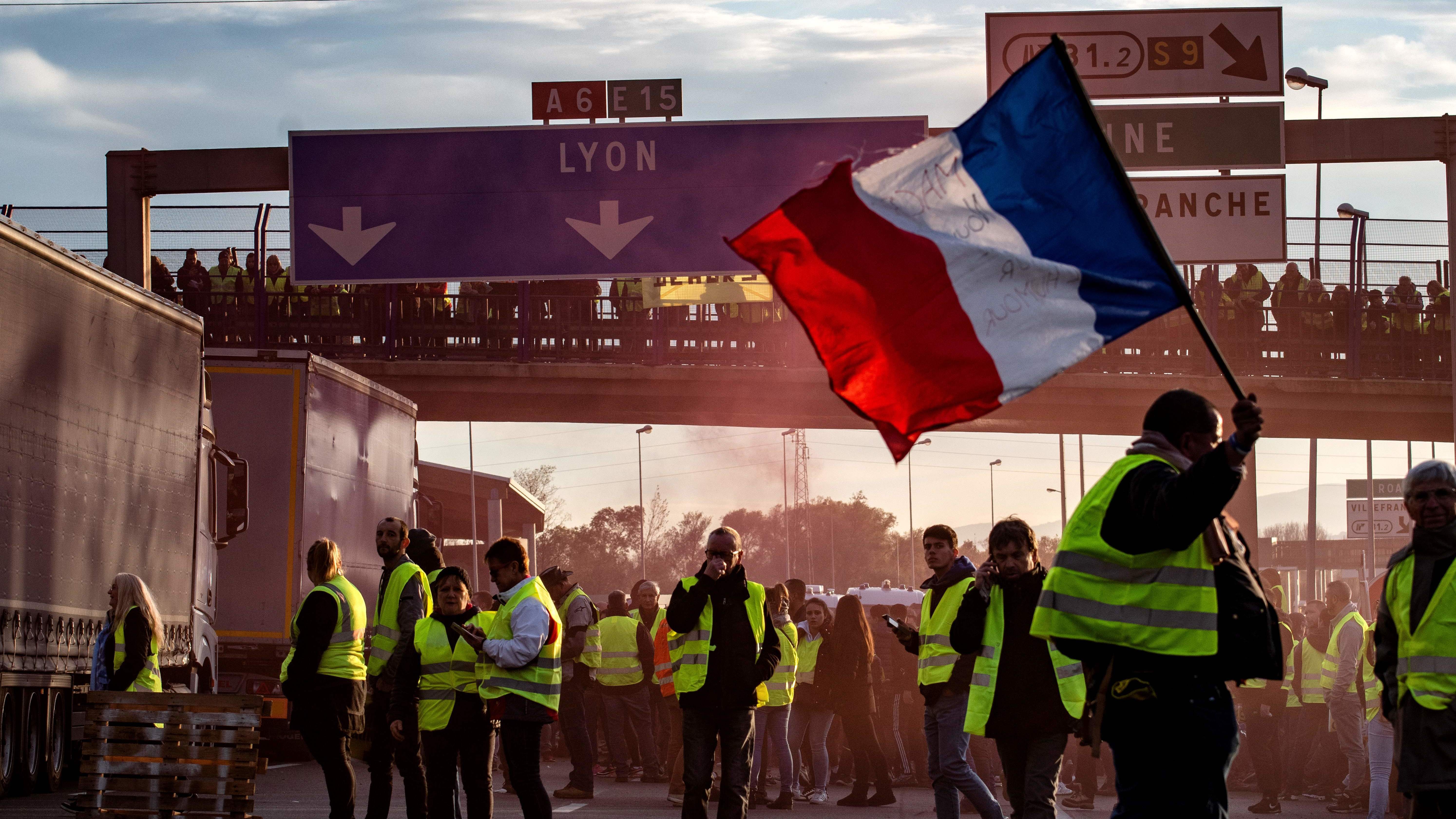 A "Yellow Vest" protester waves a French flag in Villefranche-sur-Saone on Saturday, during a demonstration against high fuel prices.