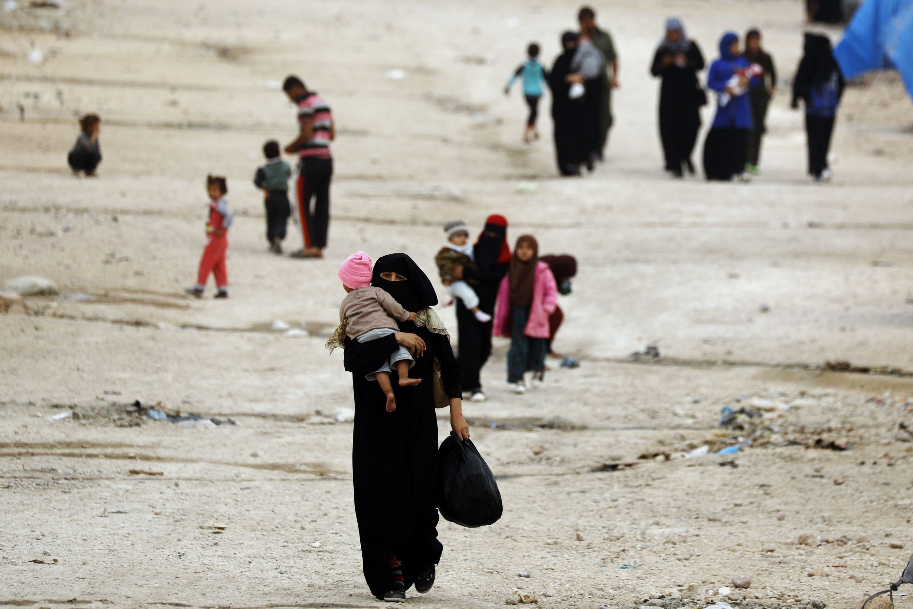 People walk through Ain Issa, one of the camps that holds displaced Syrians as well as foreign wives of ISIS fighters and their children. Thousands of foreign women and children languish in shelters in northeastern Syria, unwanted by their home governments and with no clear future. (AFP/Getty Images)