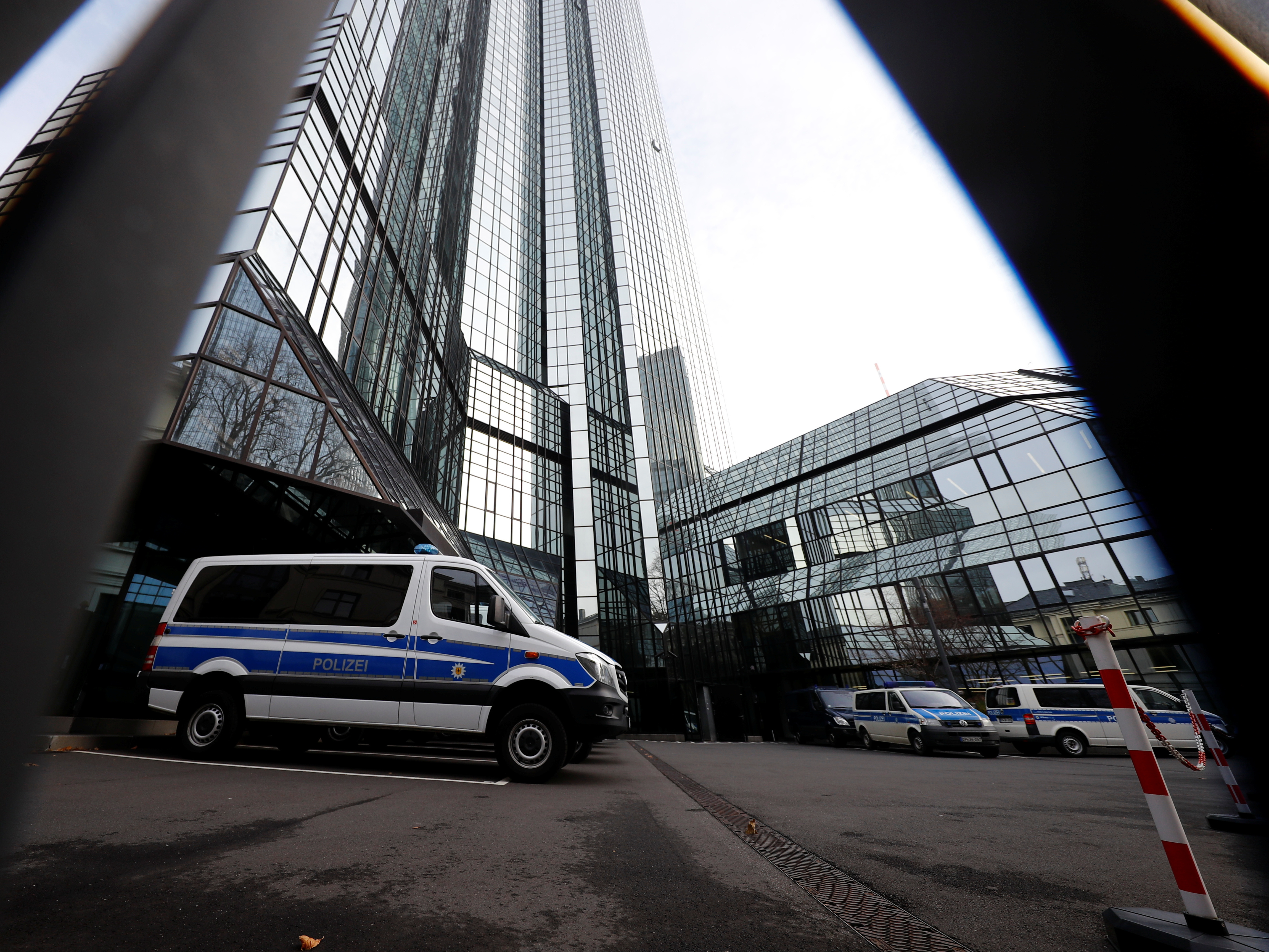Police vehicles are parked in front of Deutsche Bank headquarters as roughly 170 officers, prosecutors and tax inspectors searched the bank's offices in and around Frankfurt, Germany, on Thursday. (Reuters)