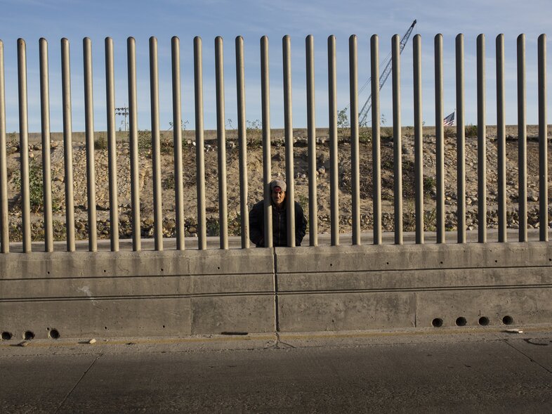 Issac Rodriguez, from Sinaloa, Mexico, peers through the fence that divides Mexico and the U.S. in Tijuana, Mexico. (Rodrigo Abd/AP)