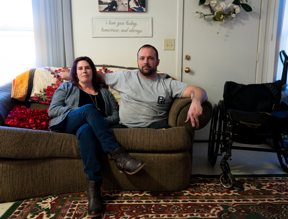 Ret. Sgt. Chris Kurtz and his wife Heather Kurtz pose for a portrait on the couch in their living room. (Erica Brechtelsbauer for NPR)