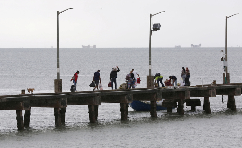 Venezuelan nationals from the city of Tucupita carry household goods that are scarce at home as they walk to board a private ferry back to their country, in the port of Cedros, southwestern Trinidad, June 8, 2016. (Andrea De Silva/Reuters)
