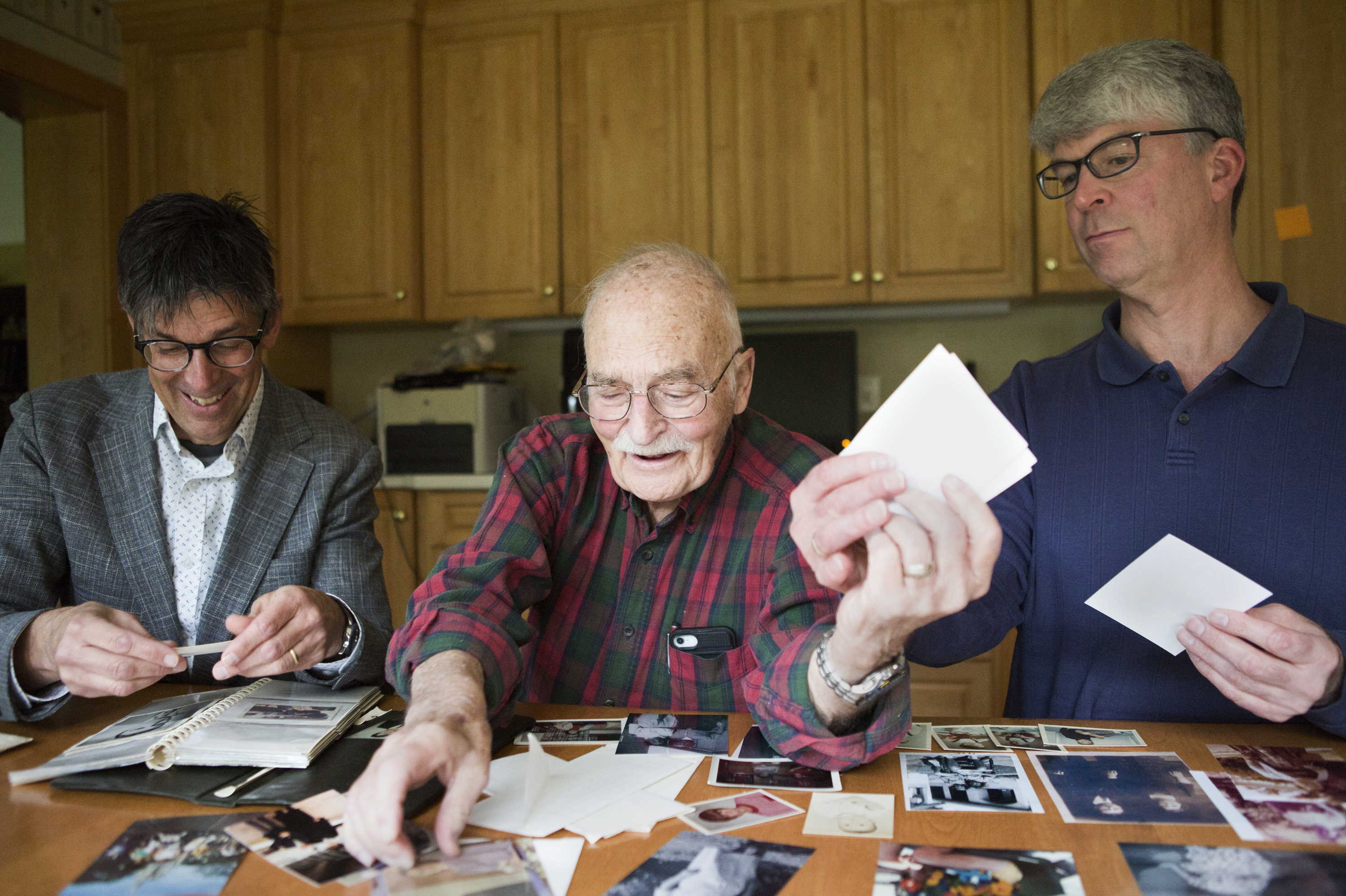 Bruce Auster (left), with his father, Stanley, and his brother, Gordon, look at family photographs at Gordon's home in Kildeer, Ill. A decades-old recording of Bruce's mother trying to convince Gordon that Santa Claus is real has brought back memories for the family.