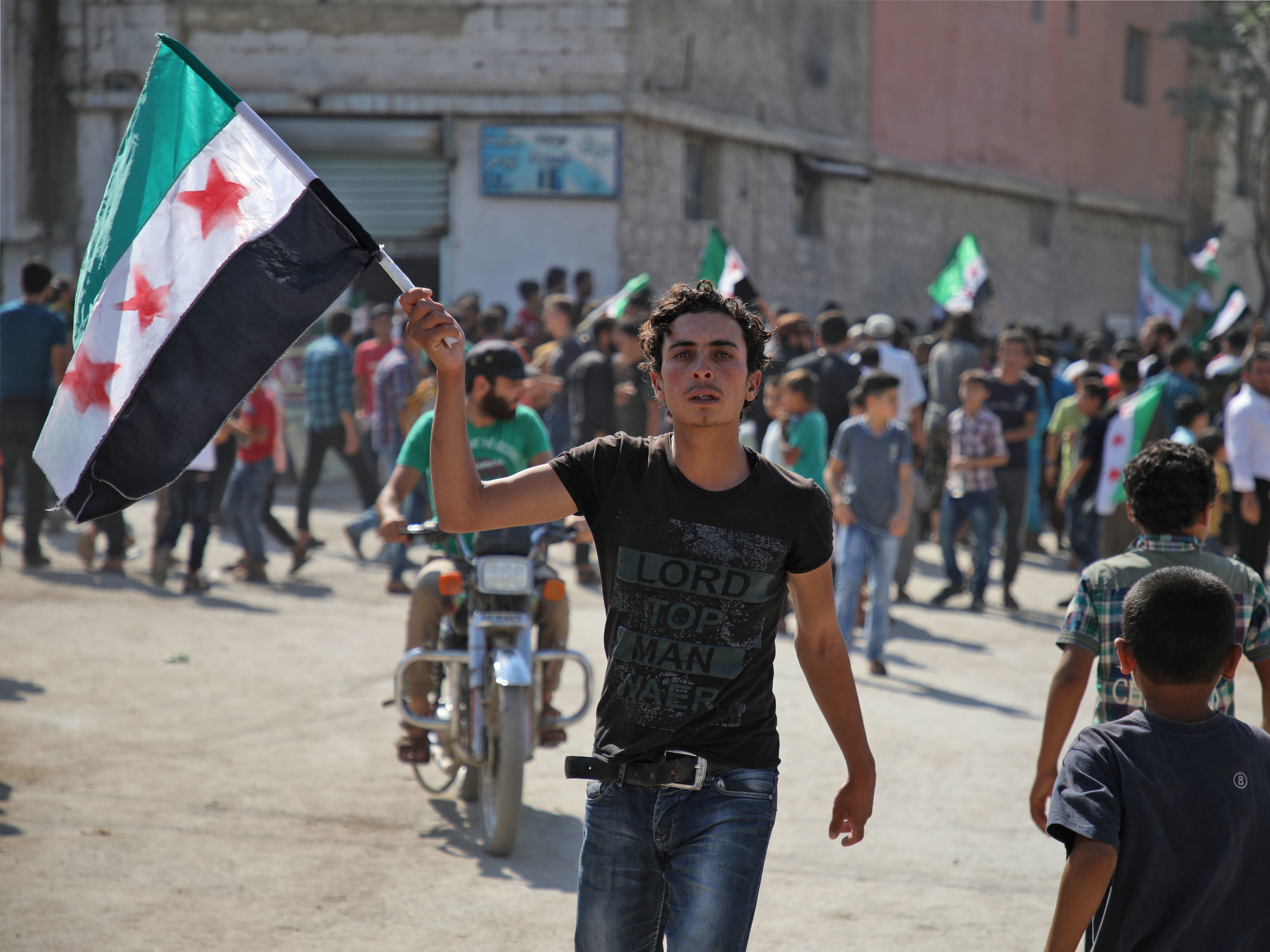 A young Syrian man waves an opposition flag during a demonstration against the Syrian government earlier this year in the rebel-held town of Hazzanu, northwest of Idlib. (AFP/Getty Images)