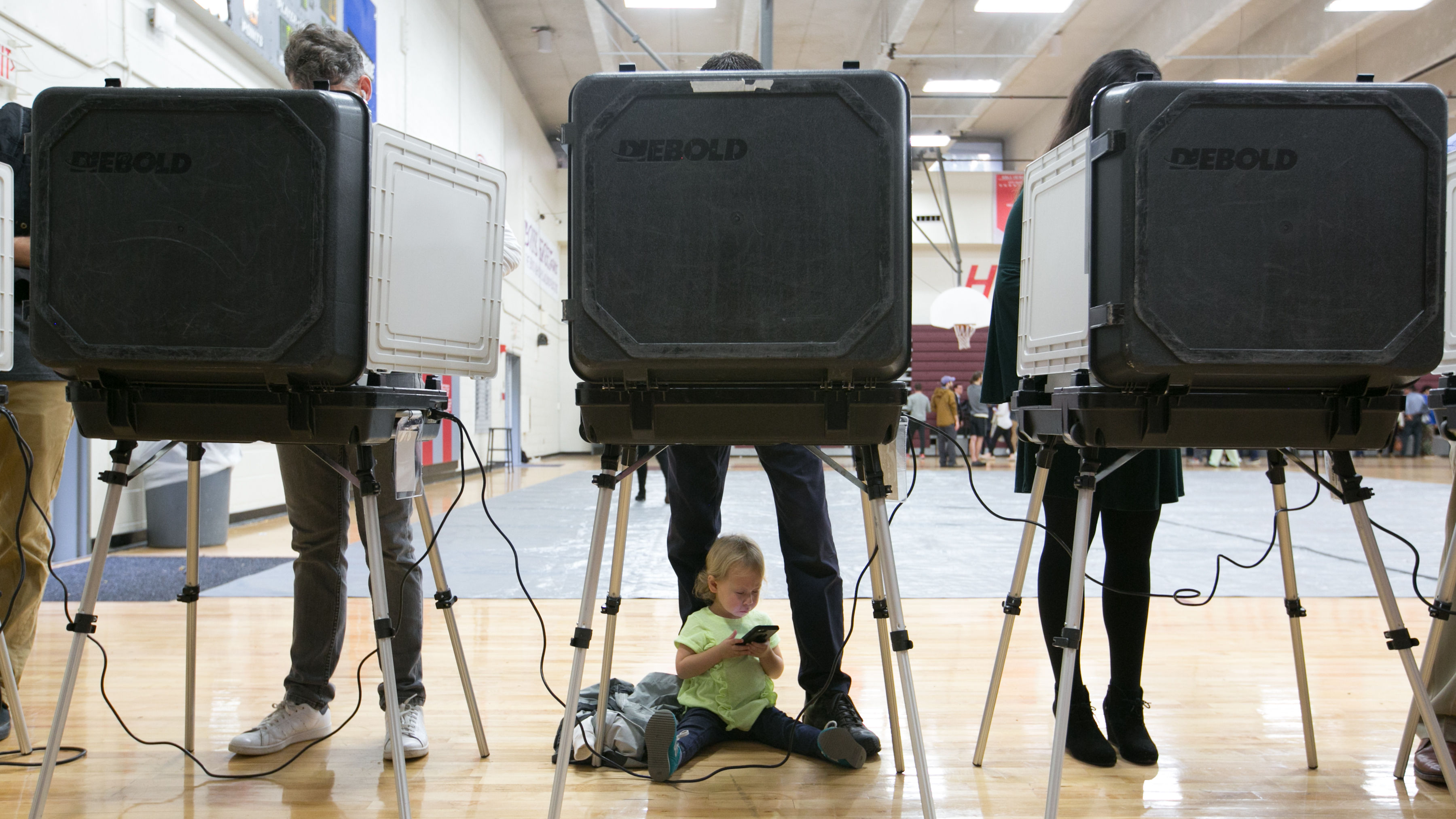 A 2-year-old waits between her father's legs as he and other voters cast their ballots at a polling station set up at Grady High School in Atlanta on Election Day. The state is one of a handful that still use voting machines that don't provide a paper record. (Getty Images)