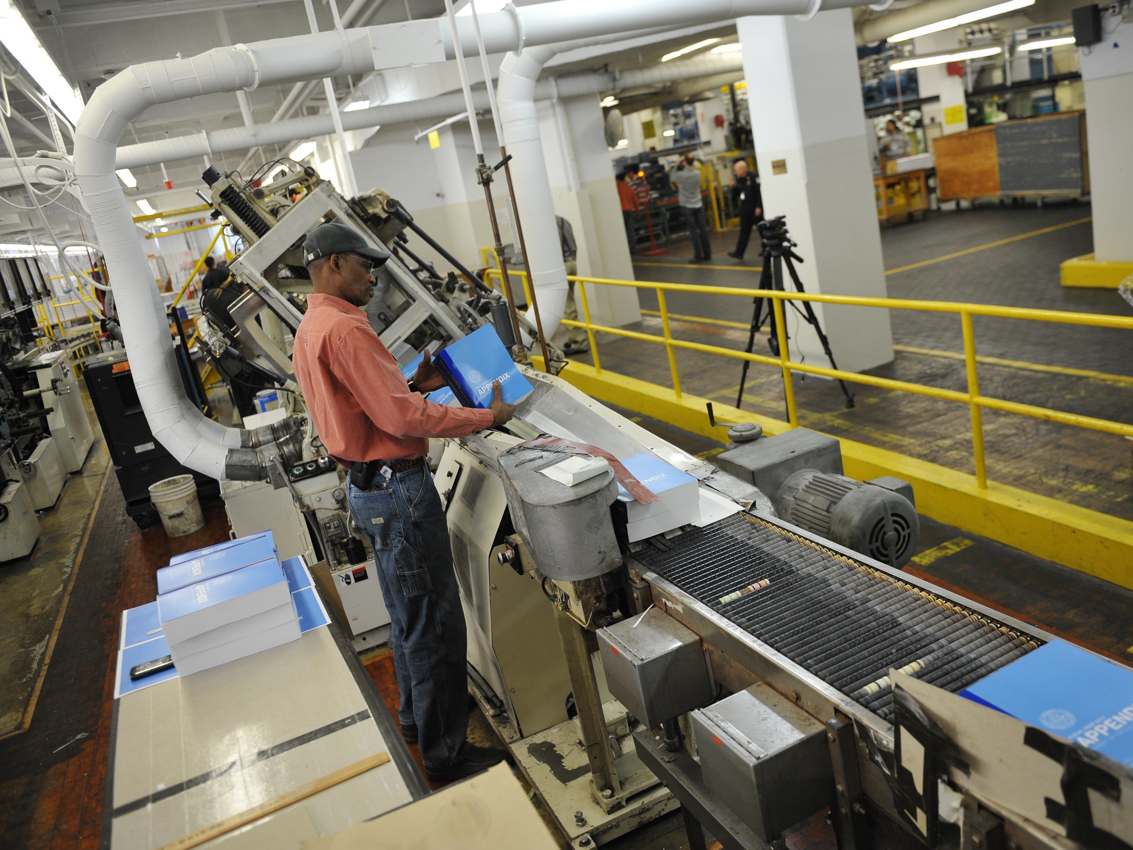 A worker checks copies of the 2012 fiscal year budget appendix before they are stacked at the Government Publishing Office in Washington, D.C.