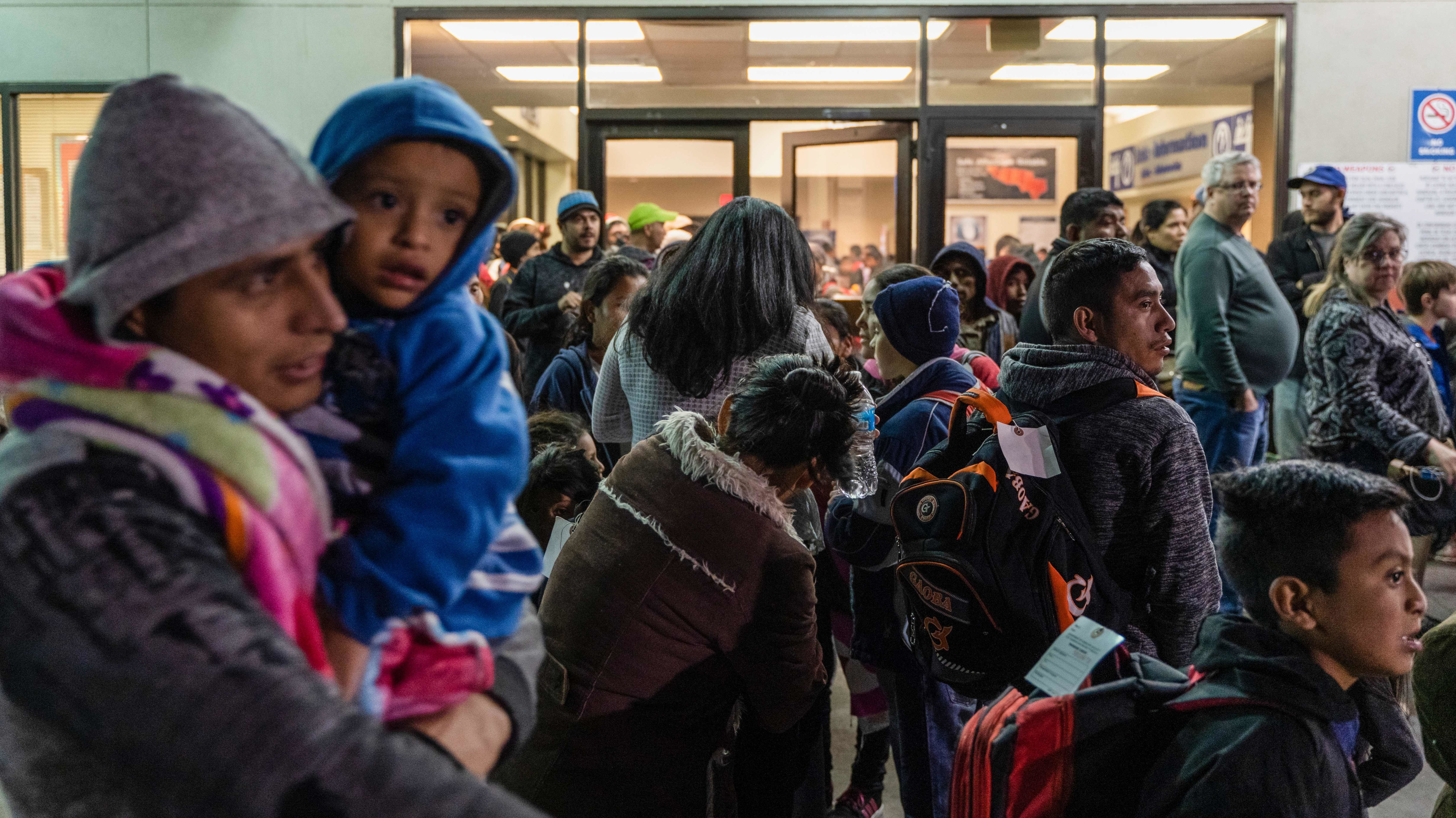Asylum seekers stand at a bus stop after they were dropped off by Immigration and Customs Enforcement at the Greyhound bus station in El Paso, Texas on Dec. 23. (AFP/Getty Images)