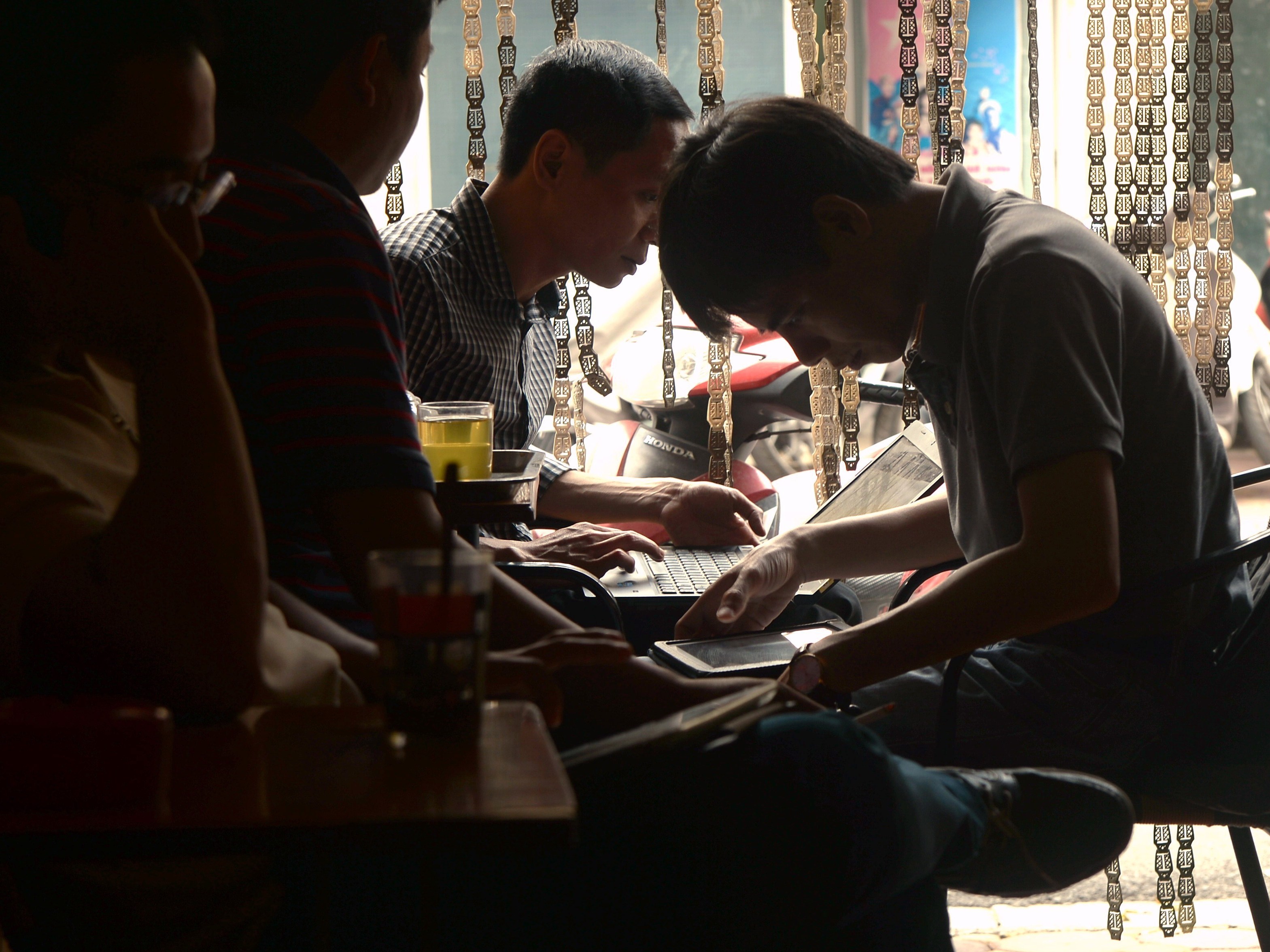 Men use tablets and laptops to check news at a coffee shop in Hanoi in 2014. Today almost half of Vietnam's population of over 95 million have access to the Internet. A new and controversial cybersecurity law goes into effect nationwide Tuesday. (AFP/Getty Images)