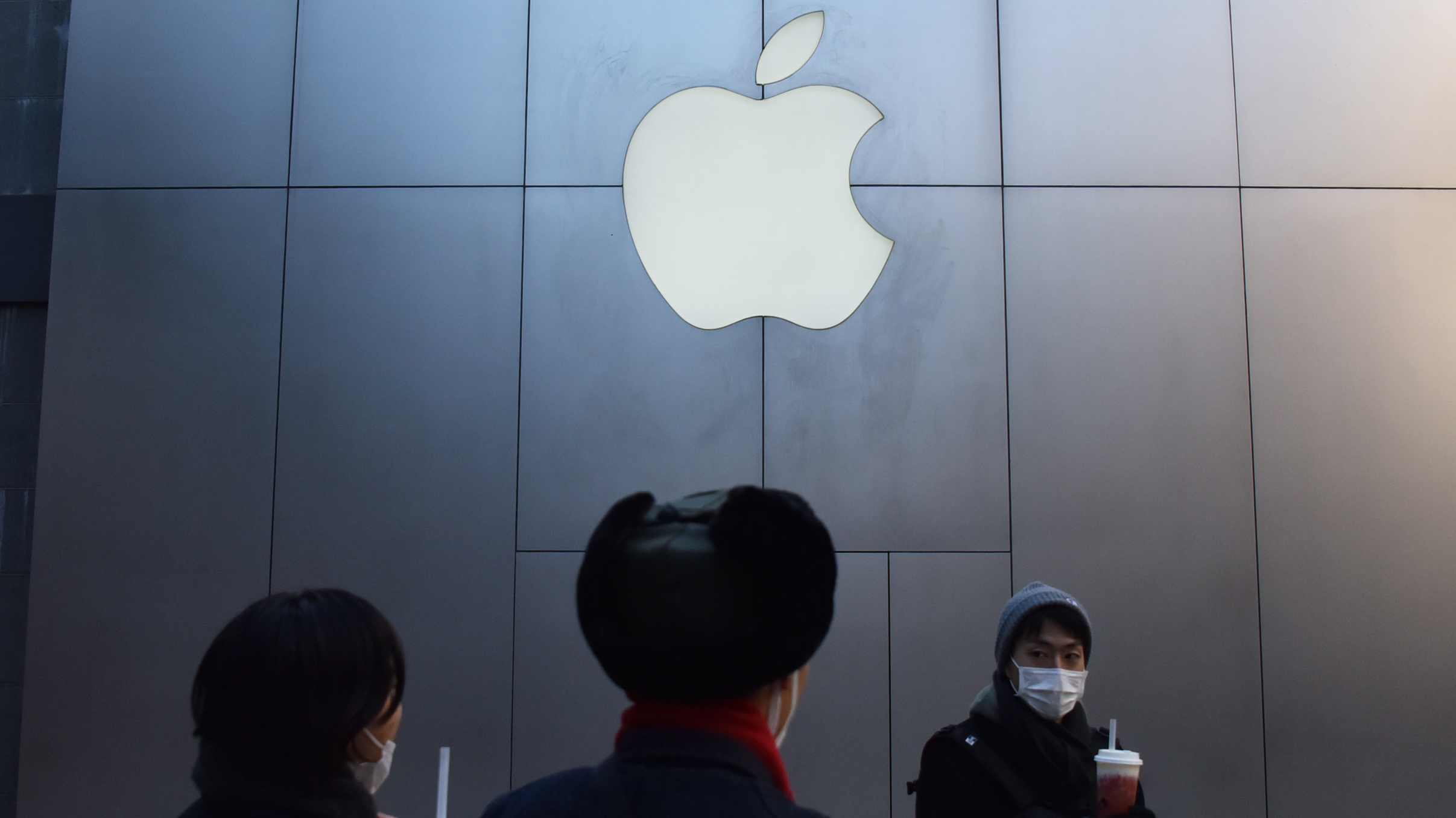 People walk past an Apple store in Beijing on Dec 11. Apple CEO cited weaker-than-expected iPhone sales in China as the company lowered its quarterly revenue estimates Wednesday.