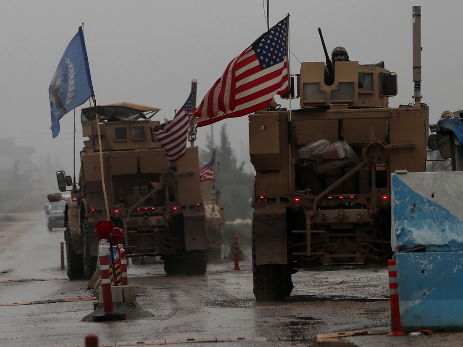 The Pentagon has "begun the process of our deliberate withdrawal from Syria," a military spokesman says. In this photo from Dec. 30, 2018, a line of U.S. military vehicles are seen at a checkpoint in northern Syria. (Delil Souleiman /AFP/Getty Images)
