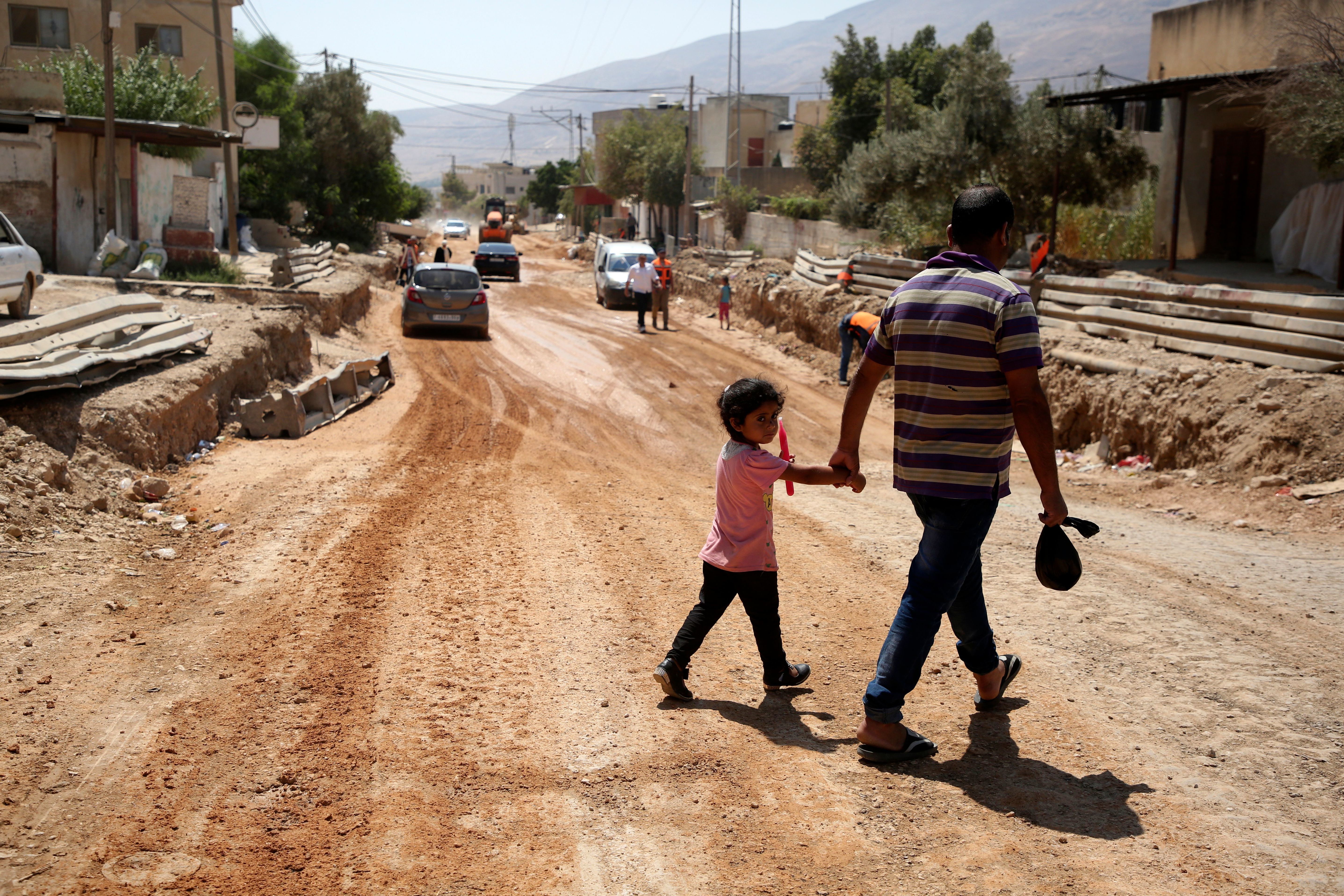 A father and his daughter cross a street under renovations as part of a U.S. aid grant in the village of al-Badhan, north of Nablus in Israeli occupied West Bank in August 2018. (AFP/Getty Images)