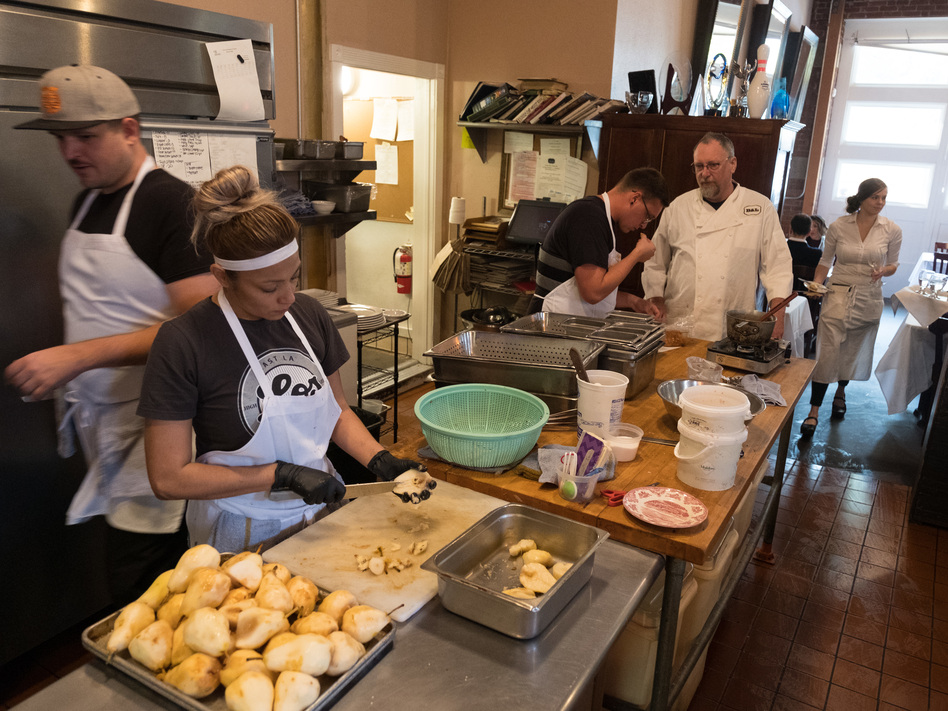 Chef Patrick Mulvaney talks with his kitchen staff as they prepare dinner at B&L restaurant.