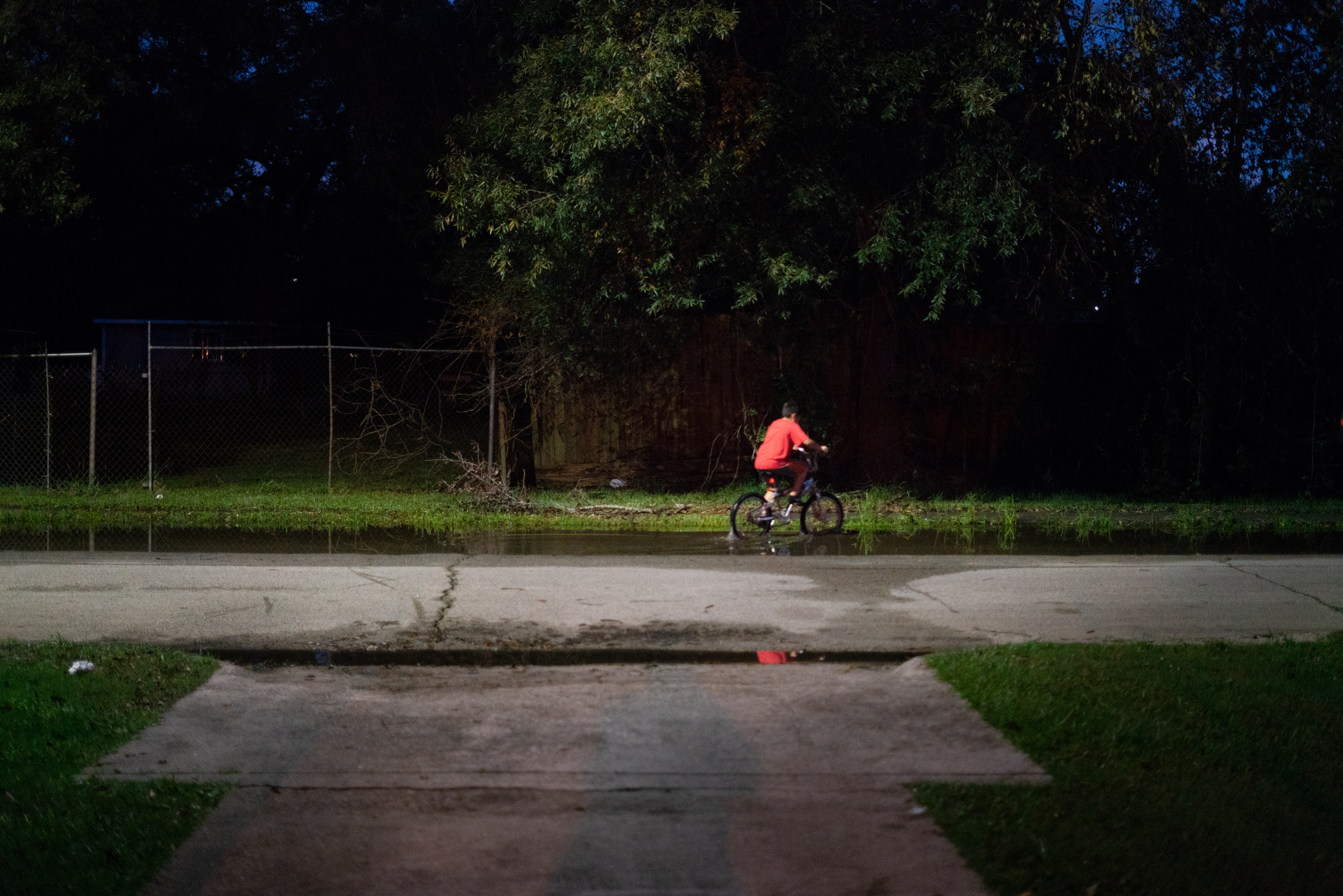 A boy rides his bike through still water after a thunderstorm in the Lakewood area of East Houston, which flooded during Hurricane Harvey. (NPR)