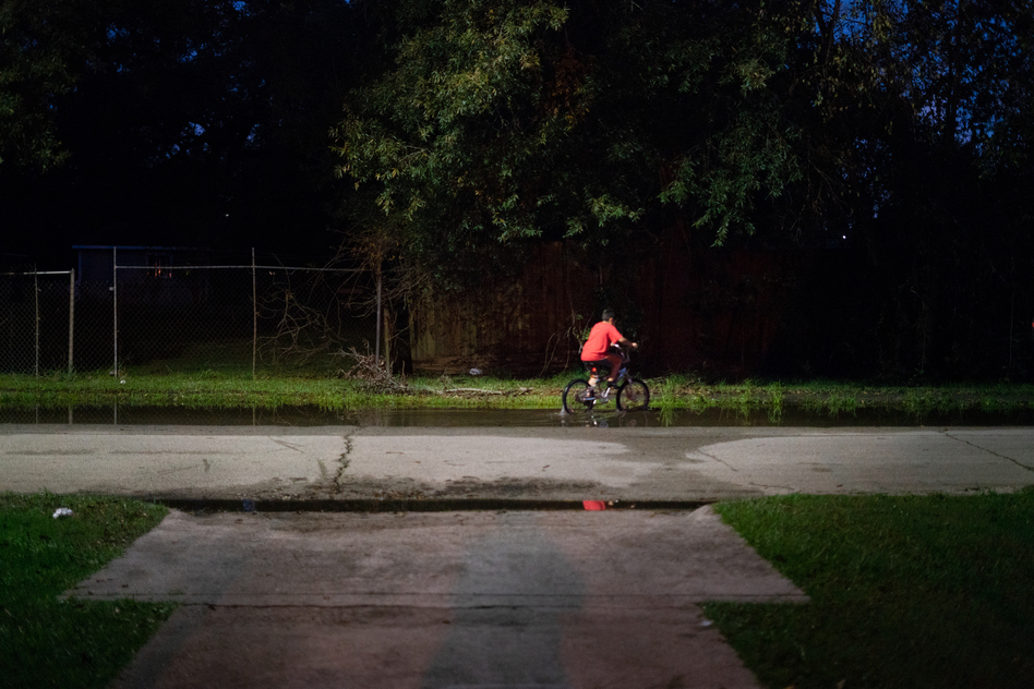 A boy rides his bike through still water after a thunderstorm in the Lakewood area of East Houston, which flooded during Hurricane Harvey. (Claire Harbage/NPR)