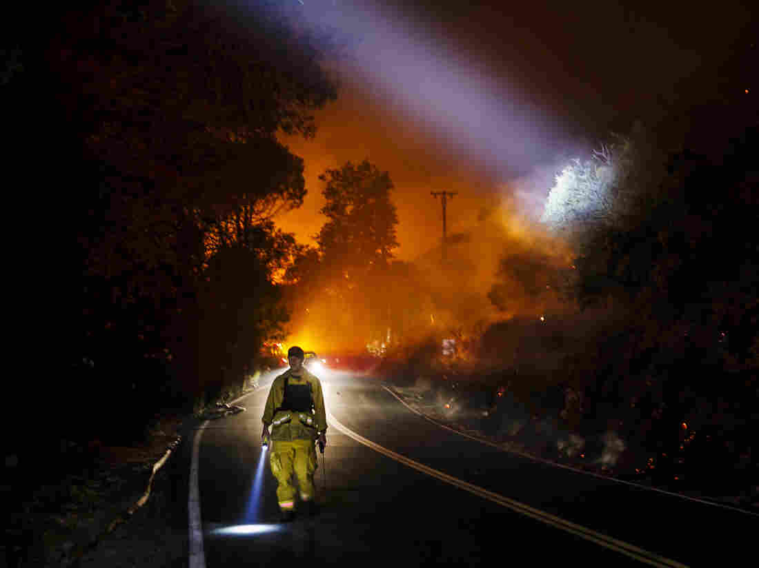 Firefighter points their beam lights around a burnt area to check for damages.