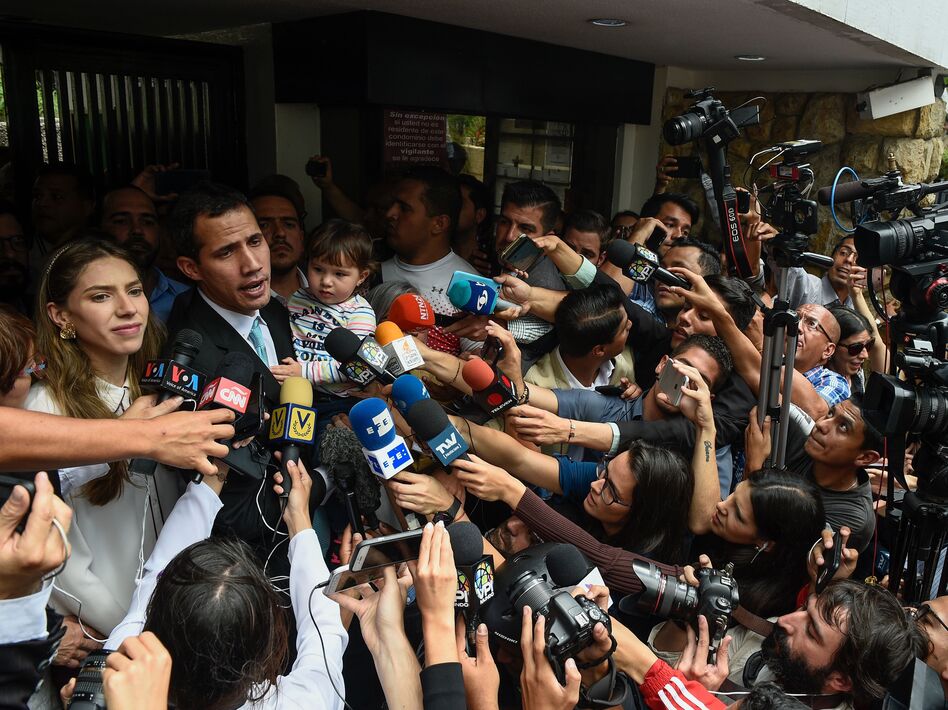 Opposition leader Juan Guaidó talks to the press as he holds his daughter, Miranda, next to his wife, Fabiana Rosales, outside his home in Caracas on Thursday. (Federico Parra/AFP/Getty Images)