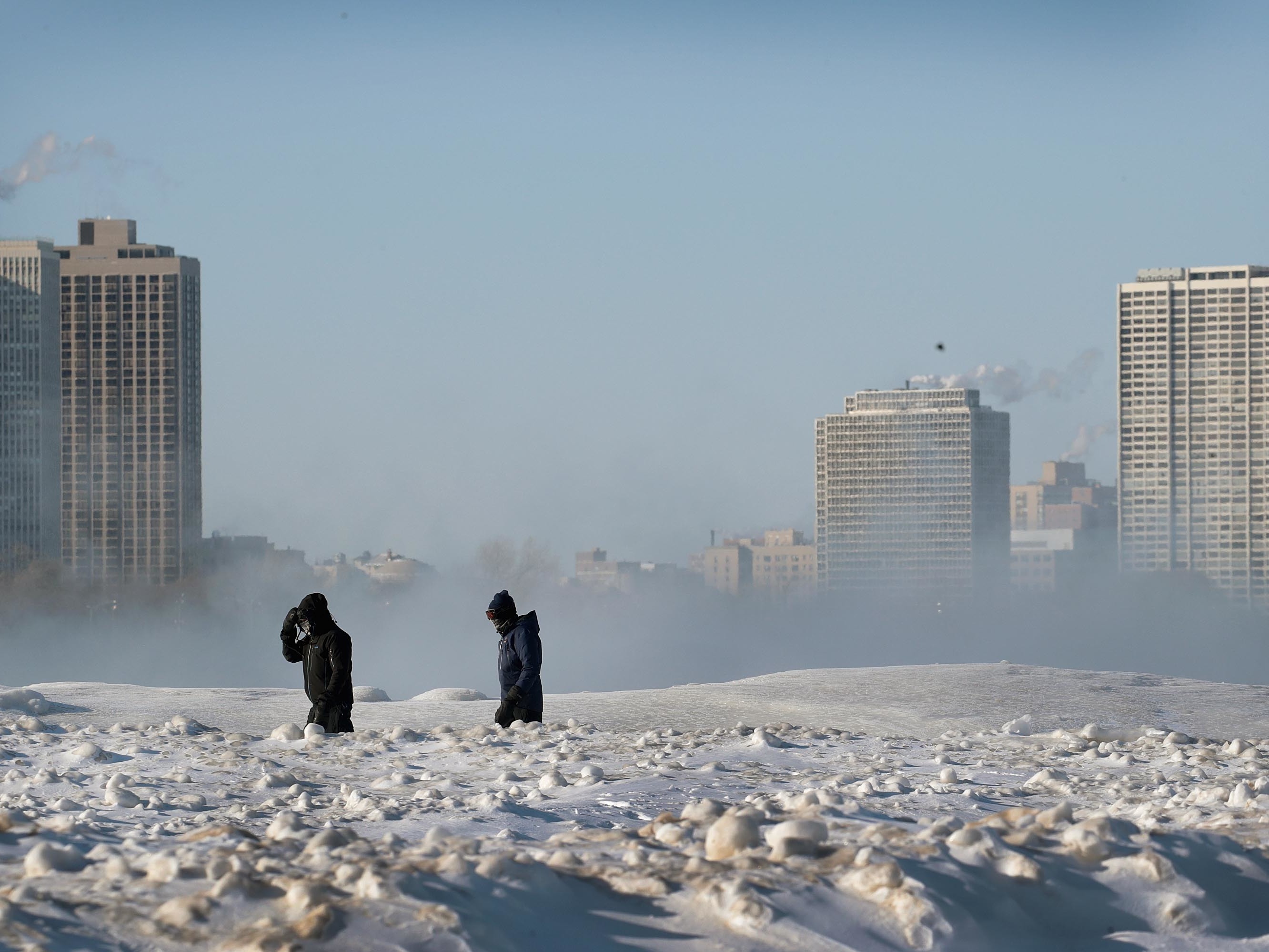 Bitterly cold temperatures continue to grip the Great Plains and Upper Midwest. People are seen here walking along the frozen lakefront on Wednesday in Chicago. (Getty Images)