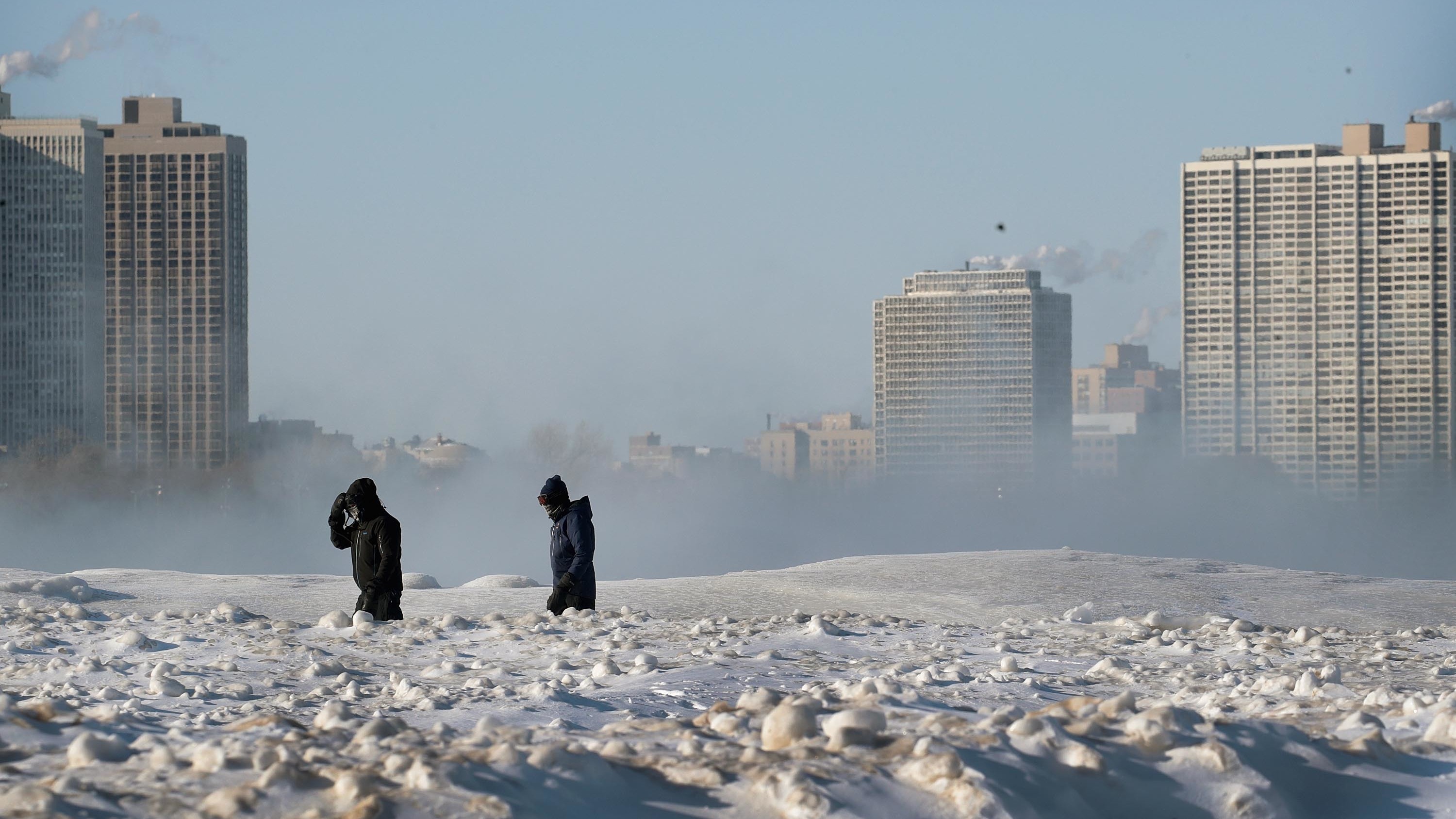 Bitterly cold temperatures continue to grip the Great Plains and Upper Midwest. People are seen here walking along the frozen lakefront on Wednesday in Chicago.
