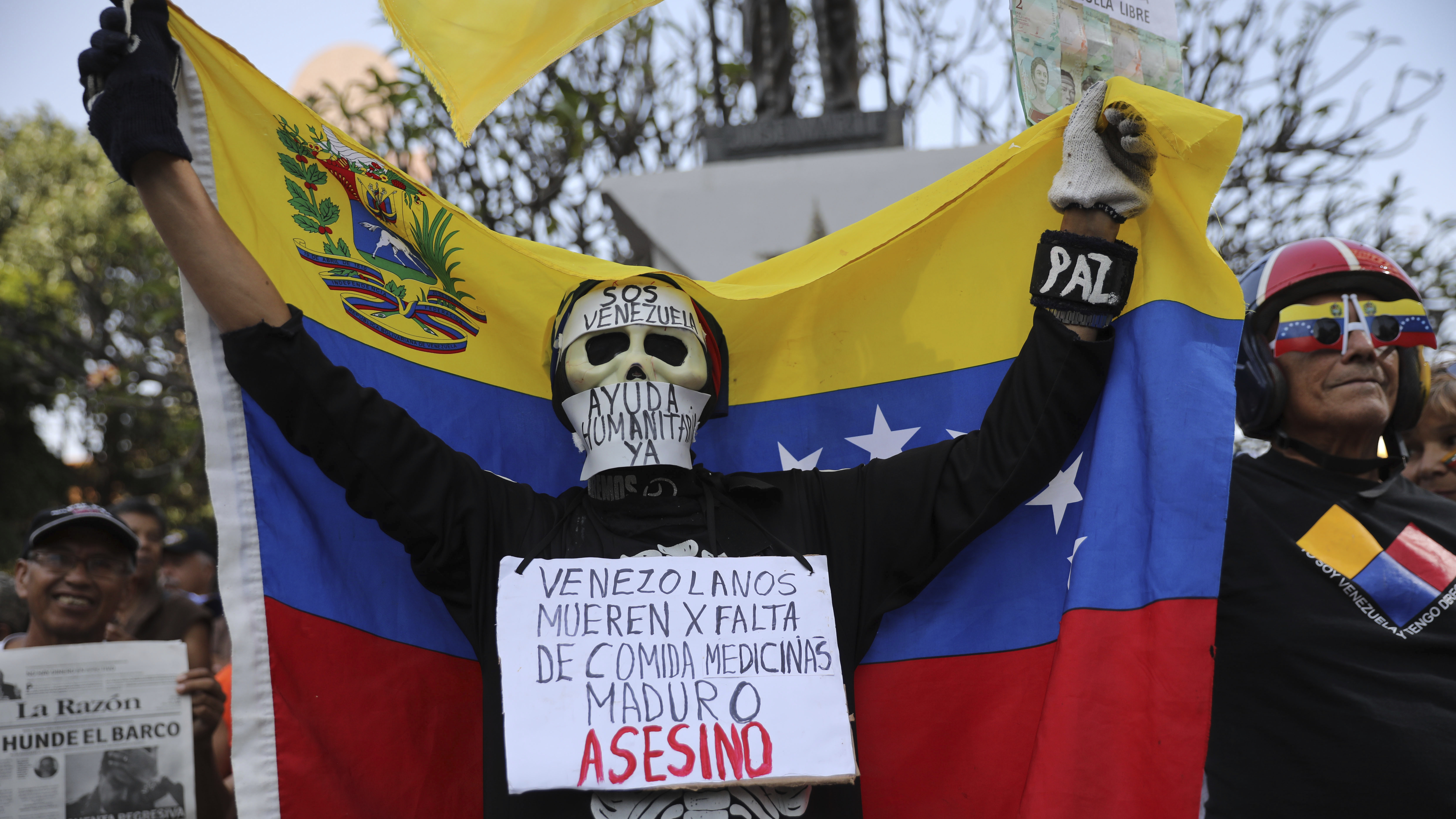 An anti-government protester on Saturday in Caracas wears a sign that reads, "Venezuelans die for lack of medicines. Maduro is an assassin." Momentum is growing for opposition leader Juan Guaidó, who has called supporters into the streets.