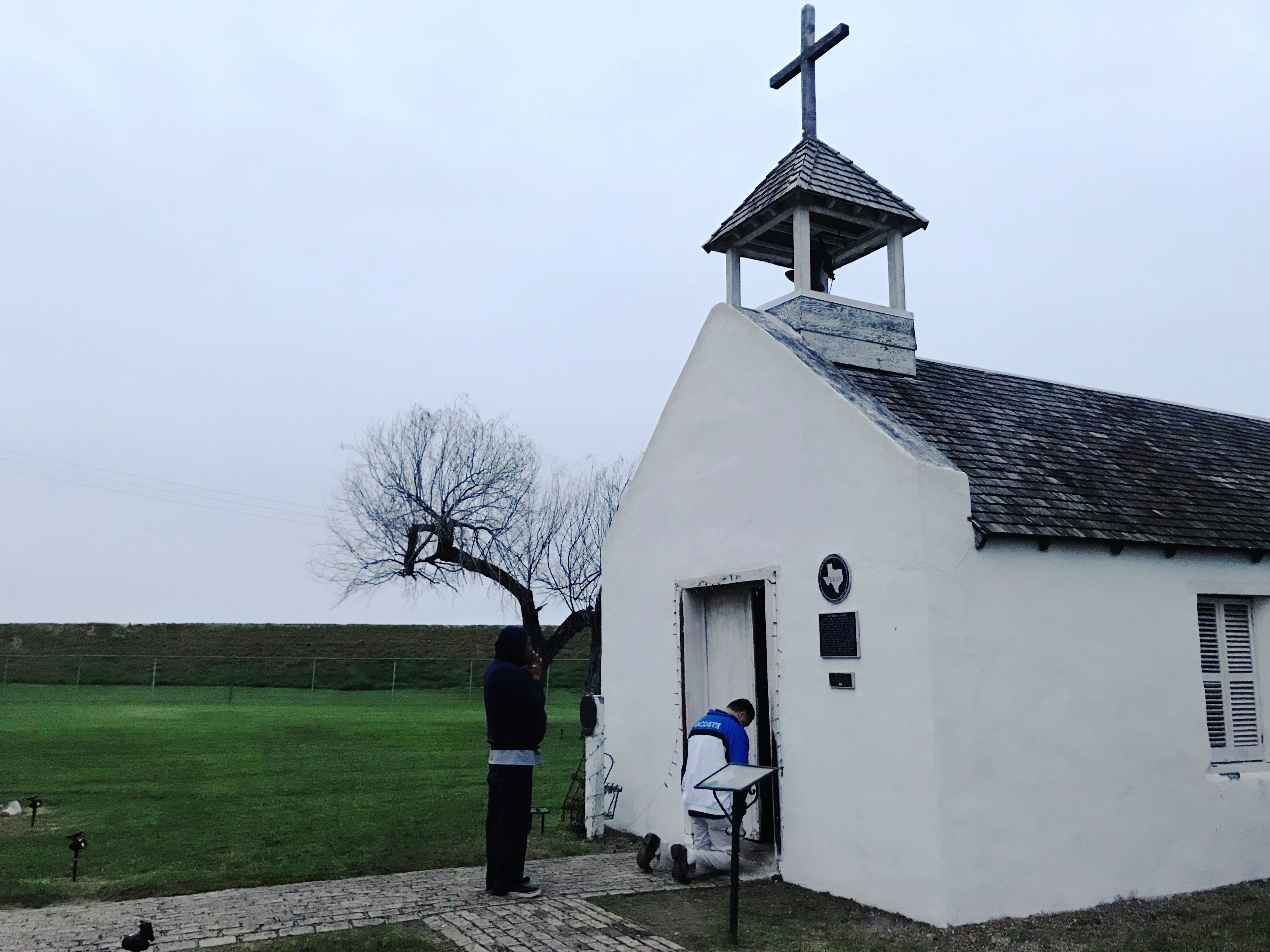 Two men pray at an early morning service at La Lomita chapel, a historical landmark in Mission, Texas. (NPR)