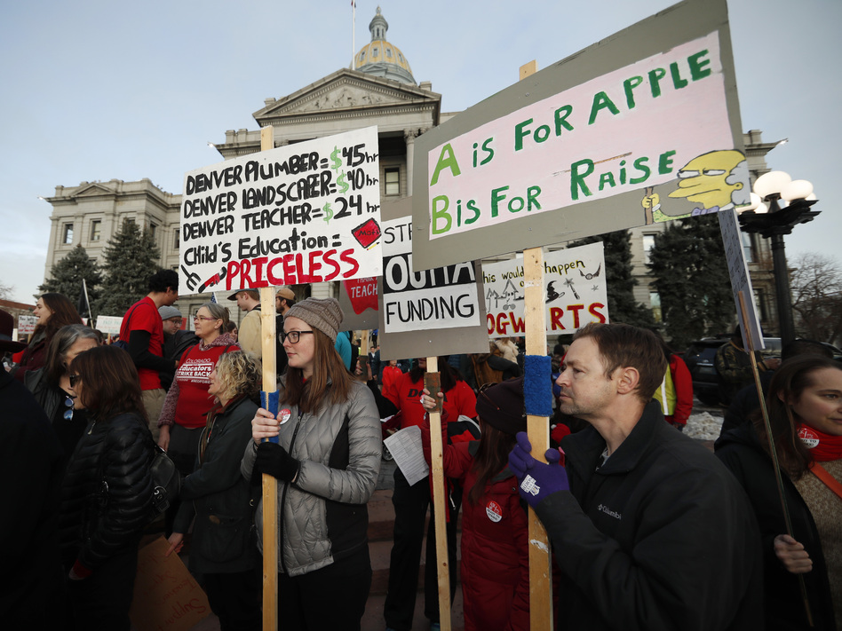 Denver teachers carry placards as they wait to march after a rally in support of a strike outside the state Capitol last month. Denver schoolteachers are going on strike over how their base pay is calculated.