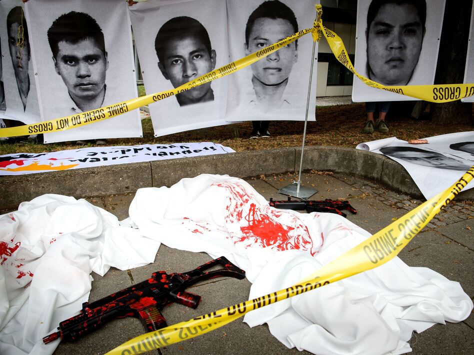 German demonstrators used crime scene tape and replica guns to draw attention to a trial over Heckler & Koch's deal that sent G36 rifles to several Mexican states that were under a ban. The company was ordered to pay a large fine on Thursday. The photos above show images of Mexican students believed to have been killed with the weapons. (Sina Schuldt /AFP/Getty Images)