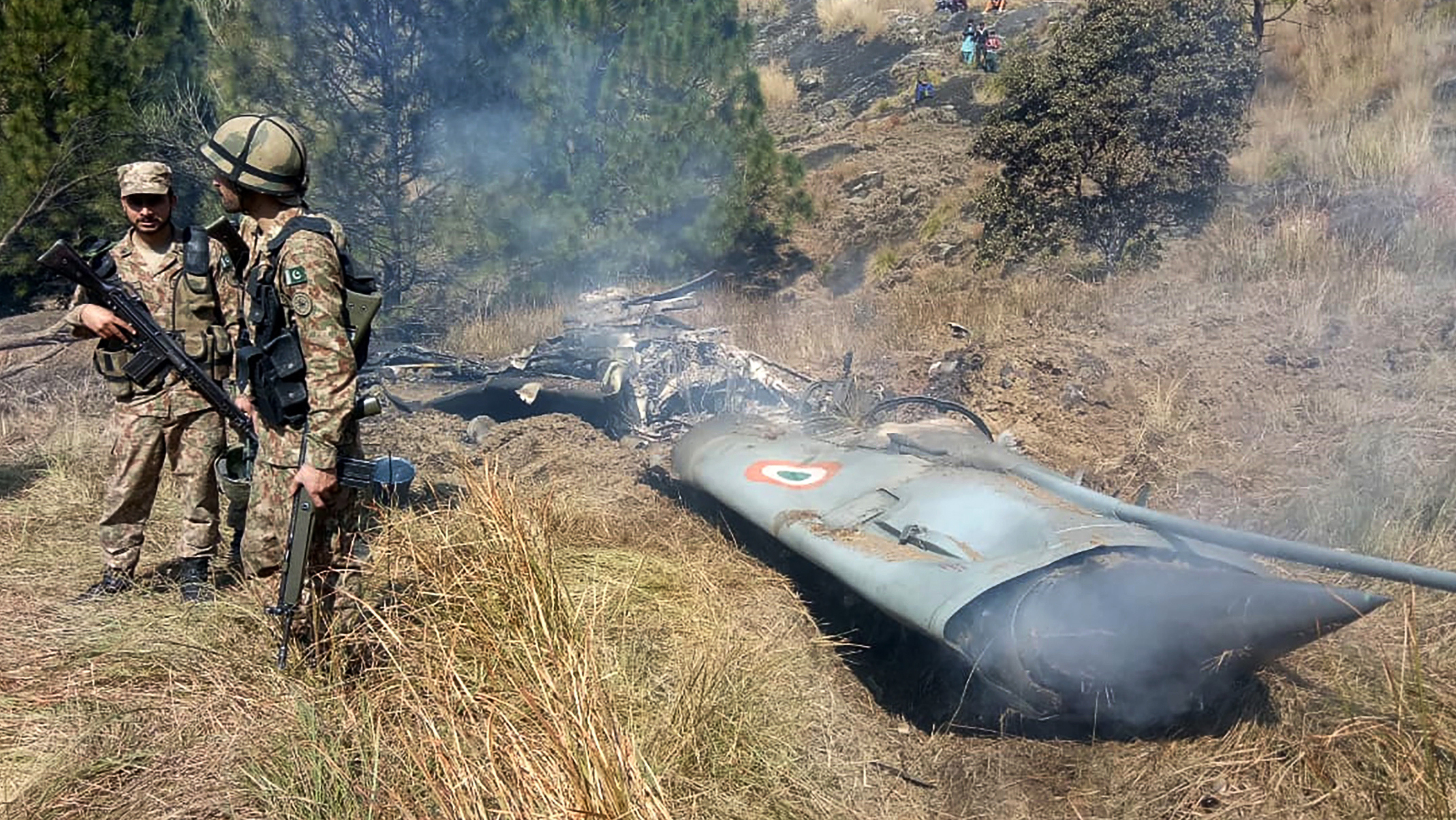 Pakistani soldiers stand next to what Pakistan says is the wreckage of an Indian fighter jet shot down in Pakistan-controlled Kashmir in the Bhimber district near the Line of Control on Wednesday. (AFP/Getty Images)