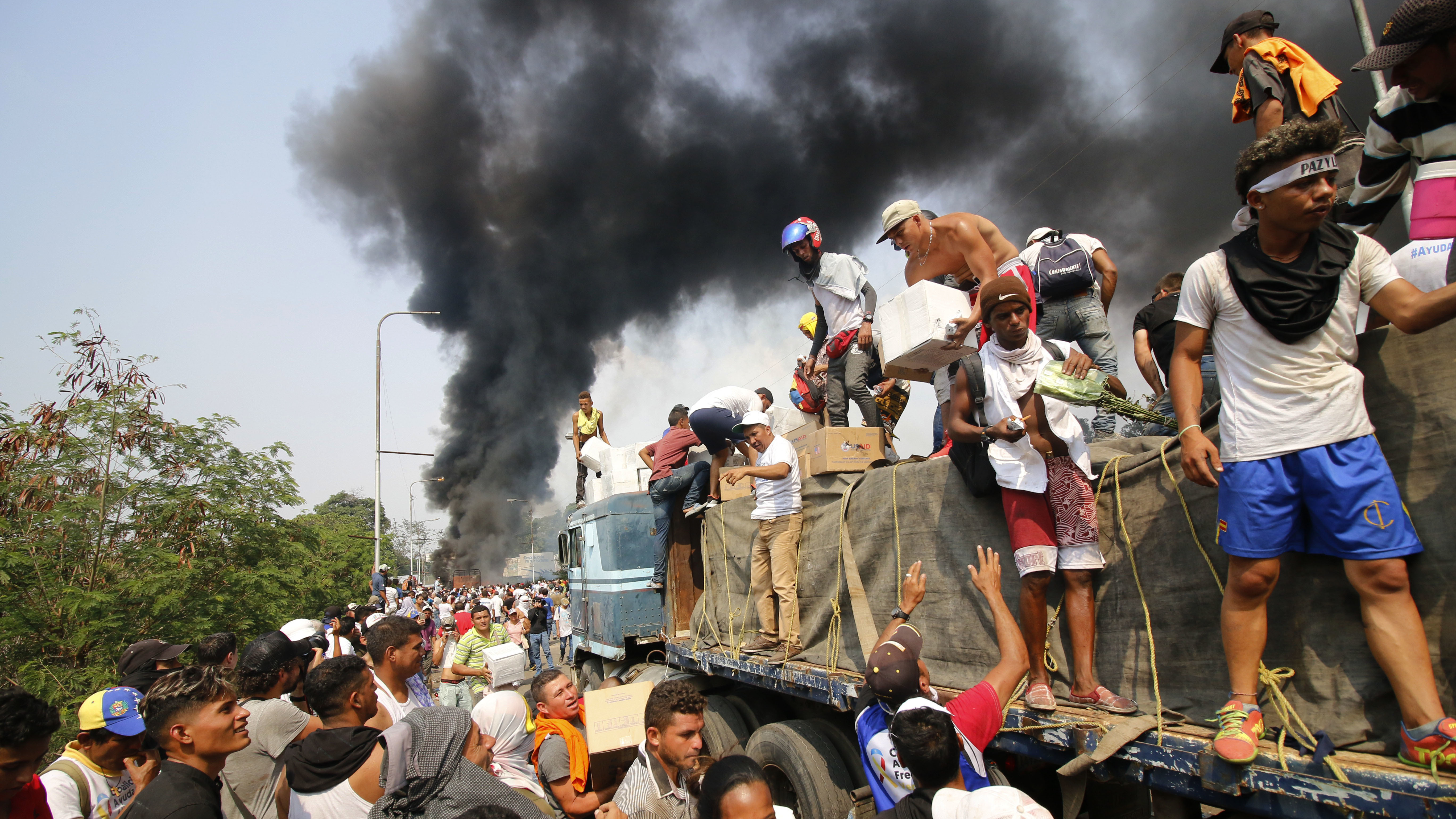 People try to salvage humanitarian aid after the truck carrying it was set ablaze on the Francisco de Paula Santander International Bridge between Colombia and Venezuela, on Feb. 23.