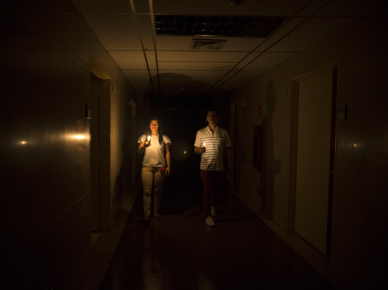 Amid a widespread power outage in Venezuela on Thursday, relatives of a patient walk in the dark halls of a health clinic in Caracas. (Ariana Cubillos/AP)