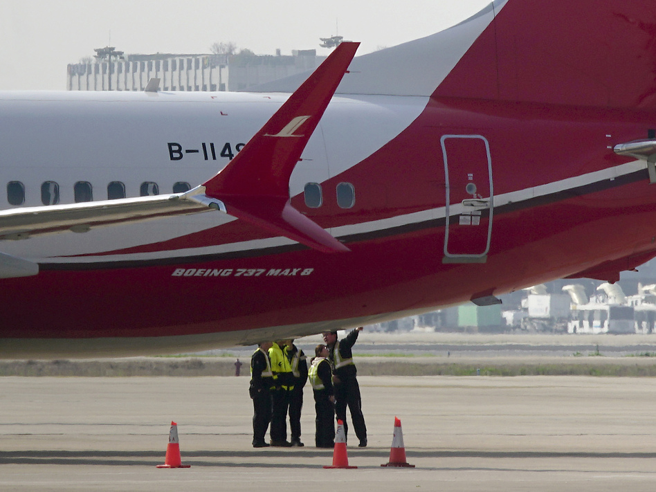 Members of the ground crew chat near a Boeing 737 Max 8 plane operated by Shanghai Airlines and parked on the tarmac at Shanghai Hongqiao International Airport in China. On Monday, the Civil Aviation Administration of China ordered all the country's airlines to ground their Boeing 737 Max 8 planes after Sunday's fatal crash of the same model plane in Ethiopia.