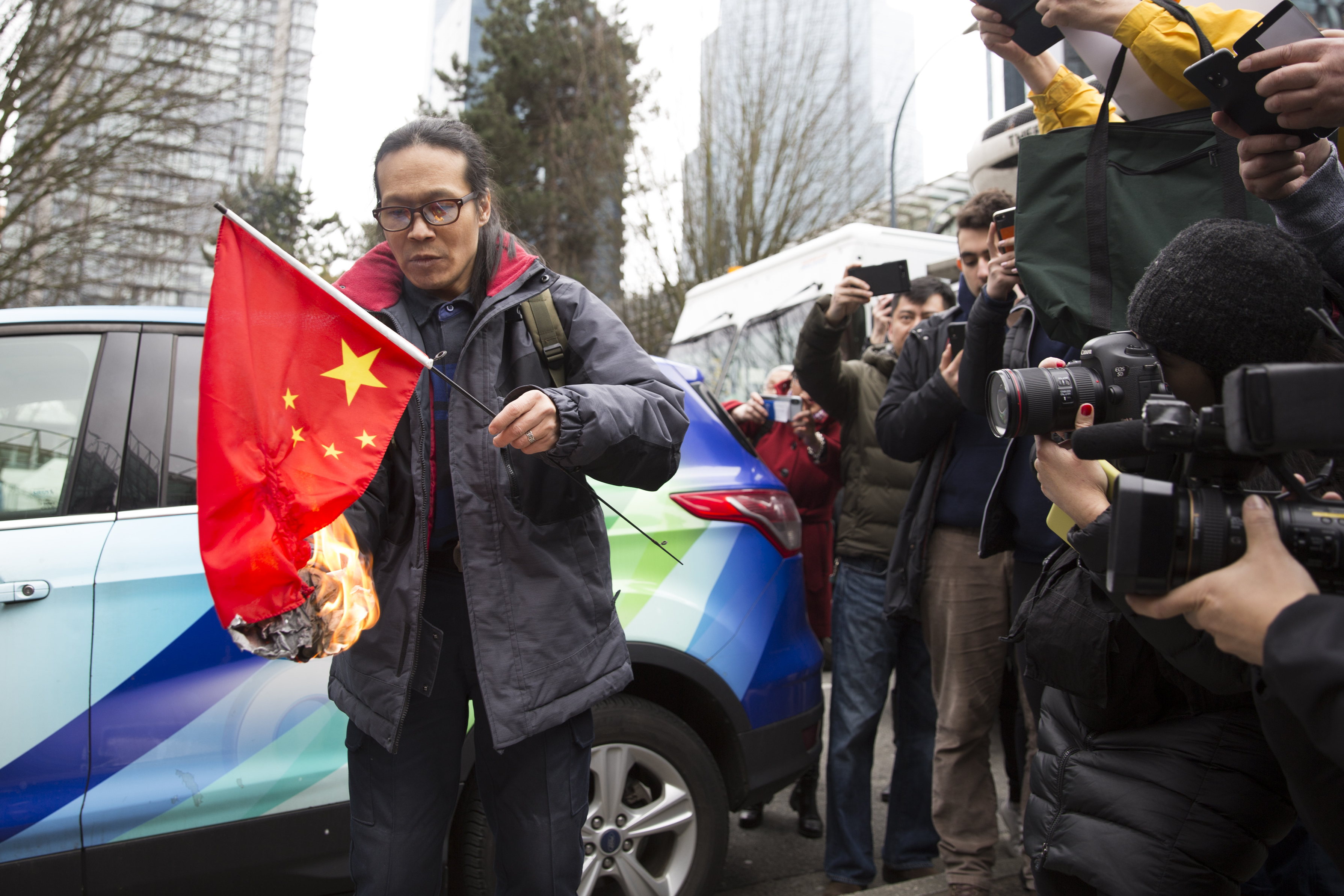 Kuang Yang burns a Chinese flag to protest human rights abuses, outside British Columbia Supreme Court in Vancouver on March 6, as Huawei Chief Financial Officer Meng Wanzhou appears in court. (AFP/Getty Images)