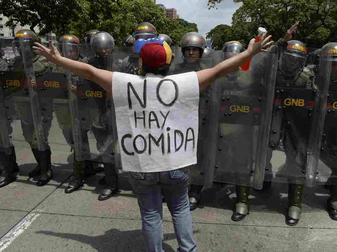 A woman with a sign reading "There is no food" protests against new emergency powers decreed this week by President Nicolas Maduro in front of a line of policemen in Caracas on May 18, 2016. / AFP / FEDERICO PARRA (Photo credit should read FEDERICO PARRA/AFP/Getty Images)