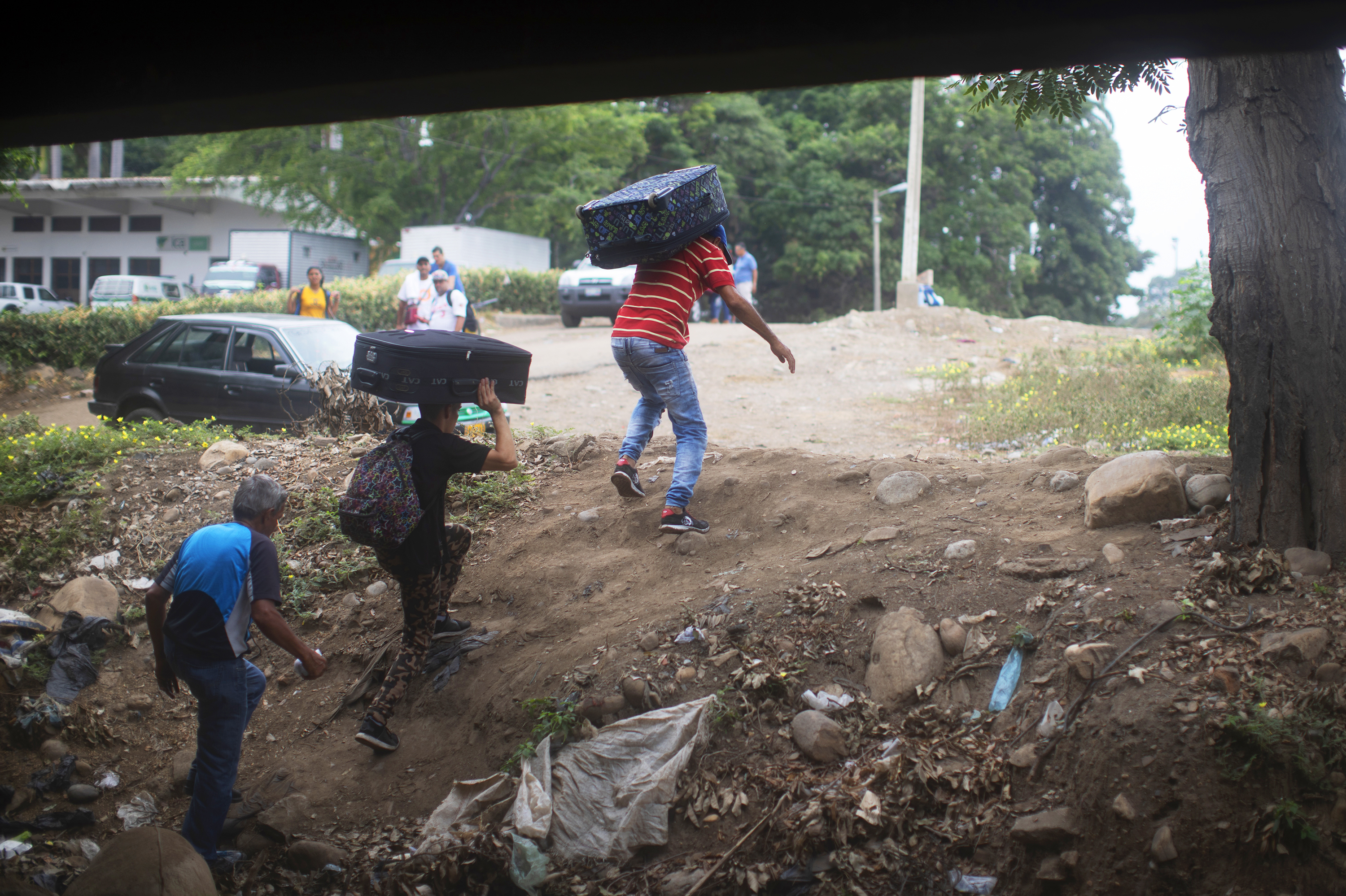Young men carry luggage from Venezuela into Colombia under the Simón Bolívar International Bridge. Tensions are rising in this border area, where many Venezuelans are seeking refuge and are anxious for change back home. (NPR)
