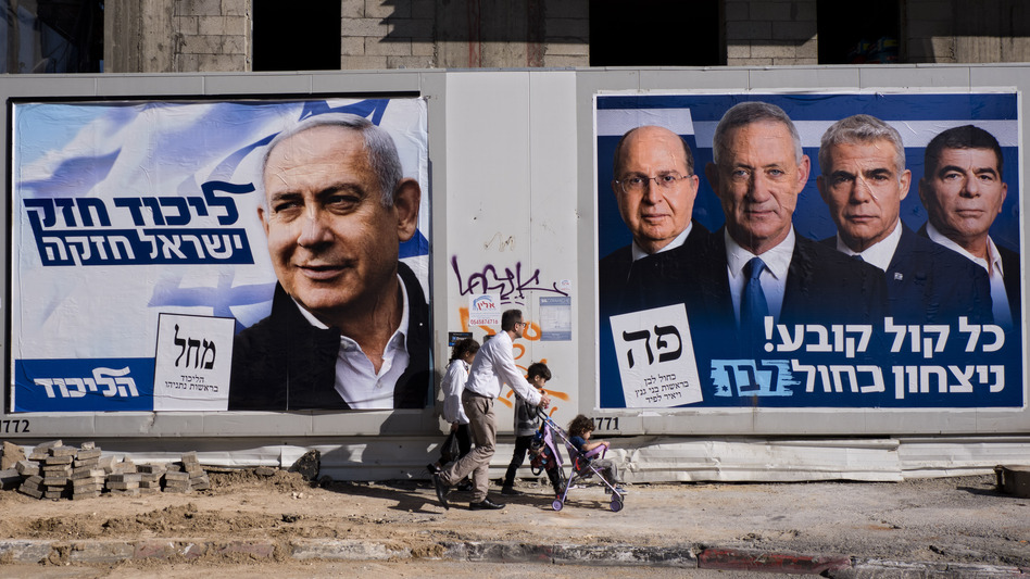 People walk by election campaign billboards showing Israeli Prime Minister and head of the Likud party Benjamin Netanyahu (left) alongside the Blue and White party leaders, including Benny Gantz. Ahead of Tuesday's election, Netanyahu has pledged to annex Israeli settlements in the occupied West Bank. (Oded Balilty/AP)
