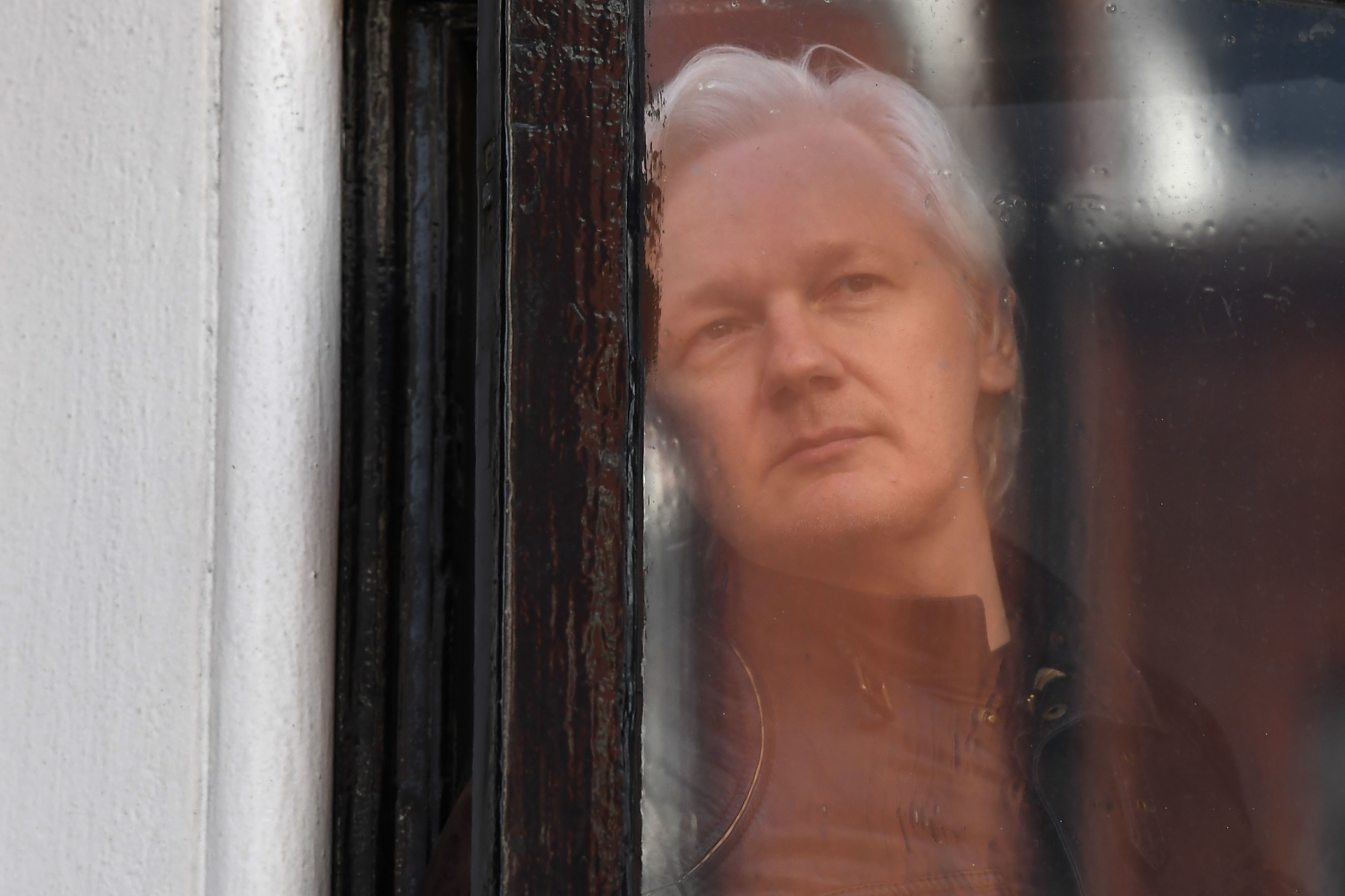 WikiLeaks founder Julian Assange appears at the window of the balcony prior to making an address to the media at the Embassy of Ecuador in London on May 19, 2017. (AFP/Getty Images)
