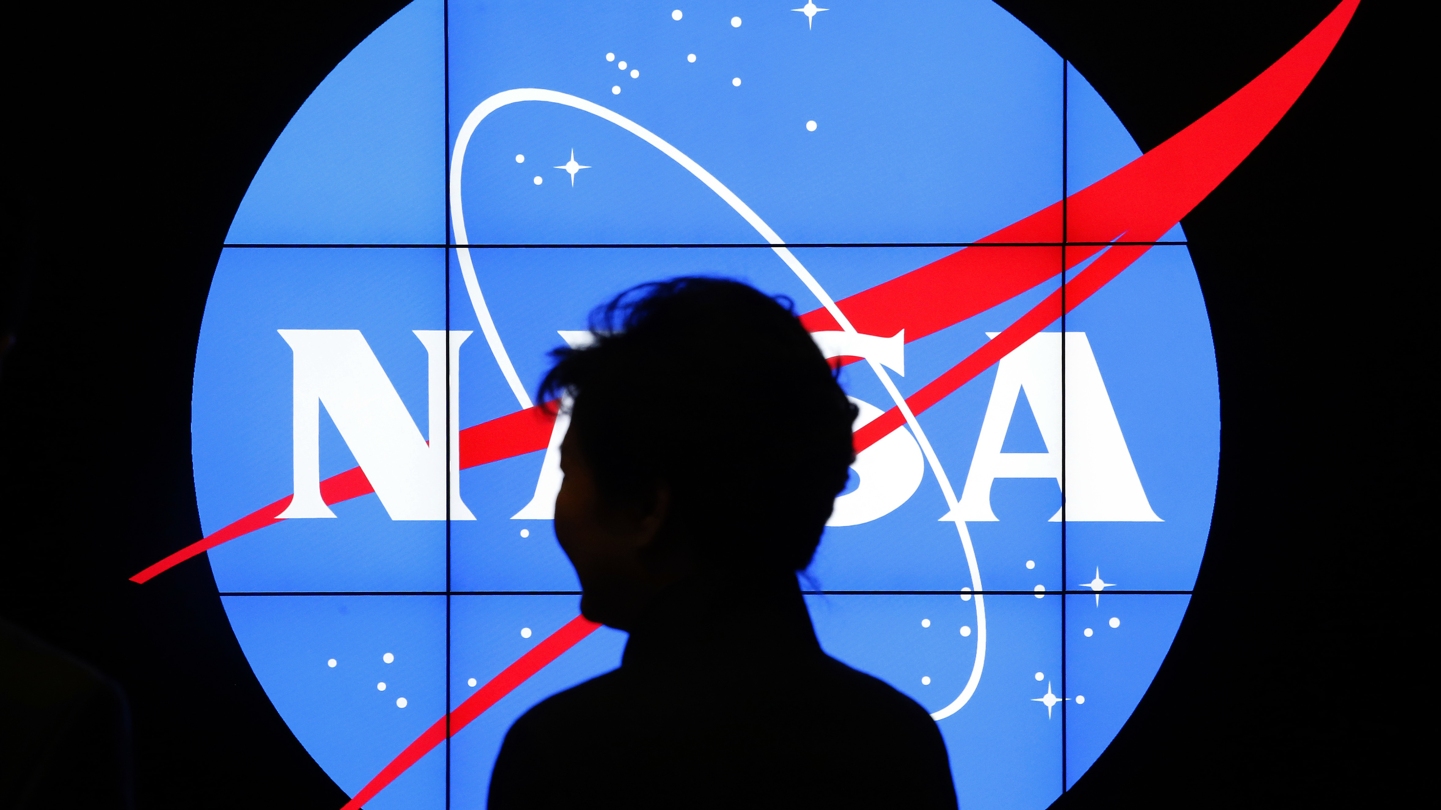 South Korean President Park Geun-hye walks past a NASA logo during a tour at the agency