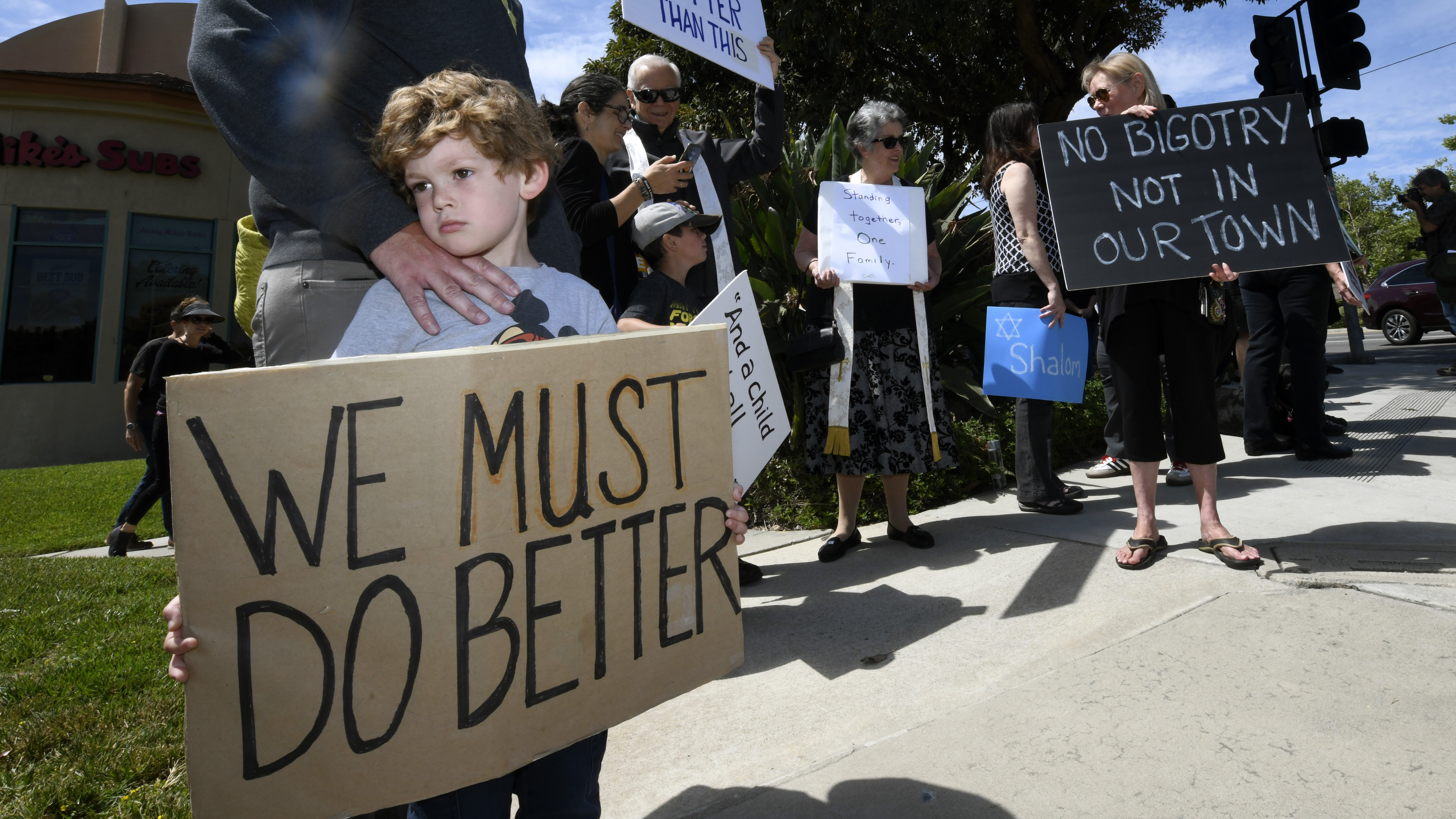 Kyle Fox, 4, and his father Brady Fox hold a sign at a Sunday vigil held to support the Chabad of Poway synagogue. A teenager opened fire at the synagogue near San Diego on Saturday, killing one and injuring three others.