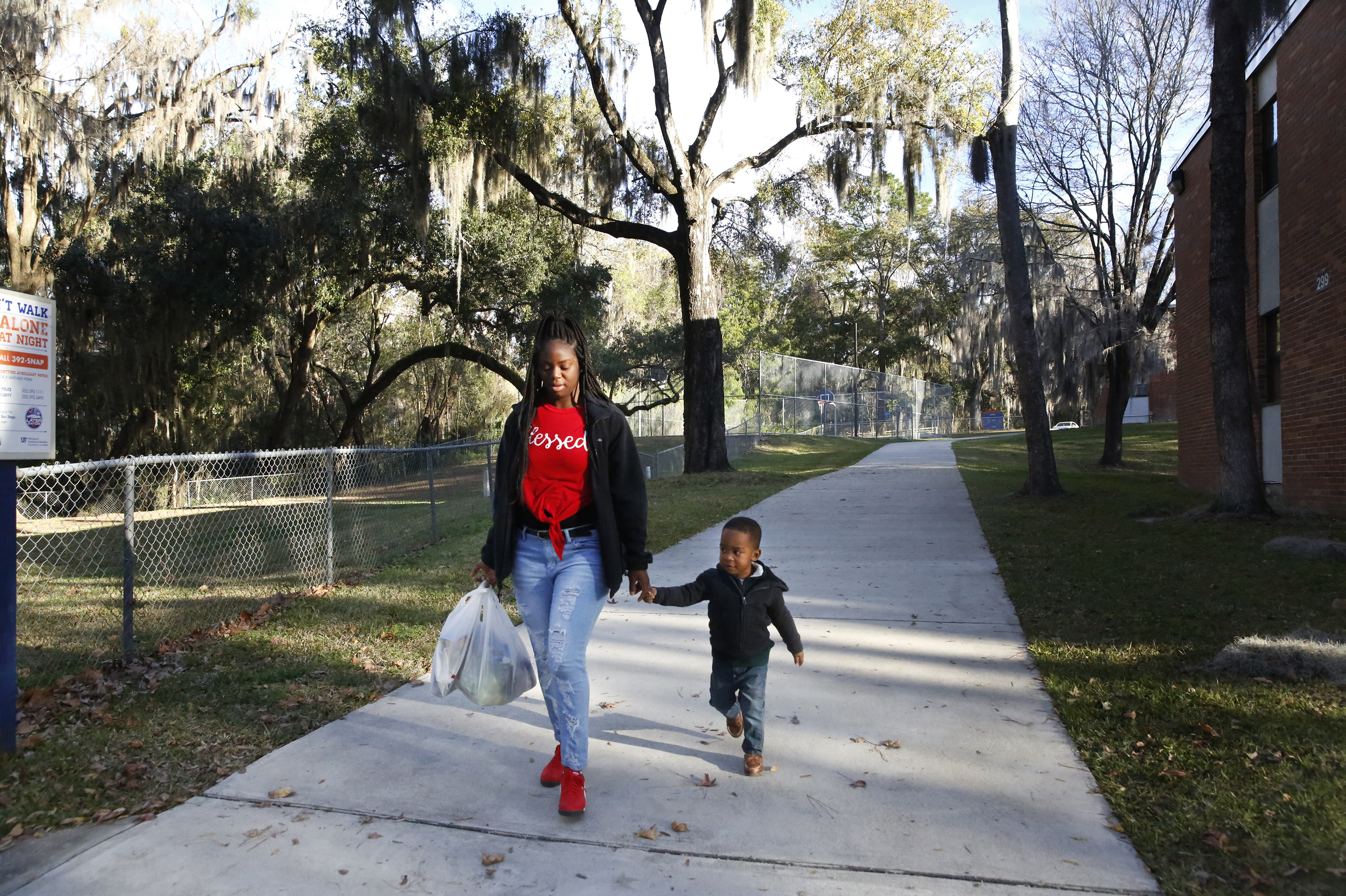 Akiya Parks, a senior at the University of Florida, and her 3-year-old son Caleb, walk through campus. (NPR)