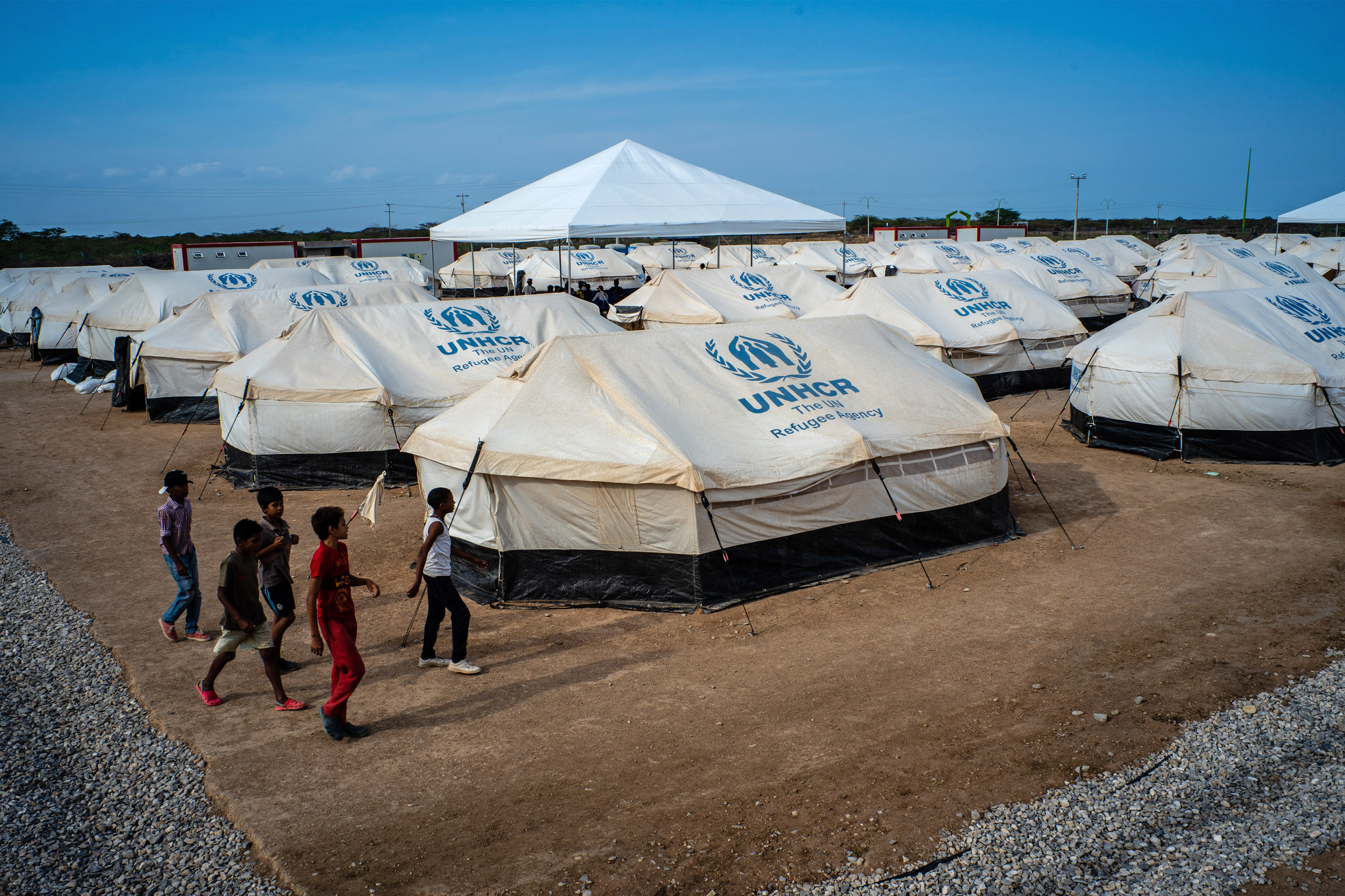 Venezuelan children walk past tents at the United Nations refugee agency camp in La Guajira, Colombia, in April. Local and national government agencies called on the UNHCR for aid after tens of thousands of Venezuelan migrants and refugees crossed the border into the Colombian town of Maicao. (Bloomberg via Getty Images)
