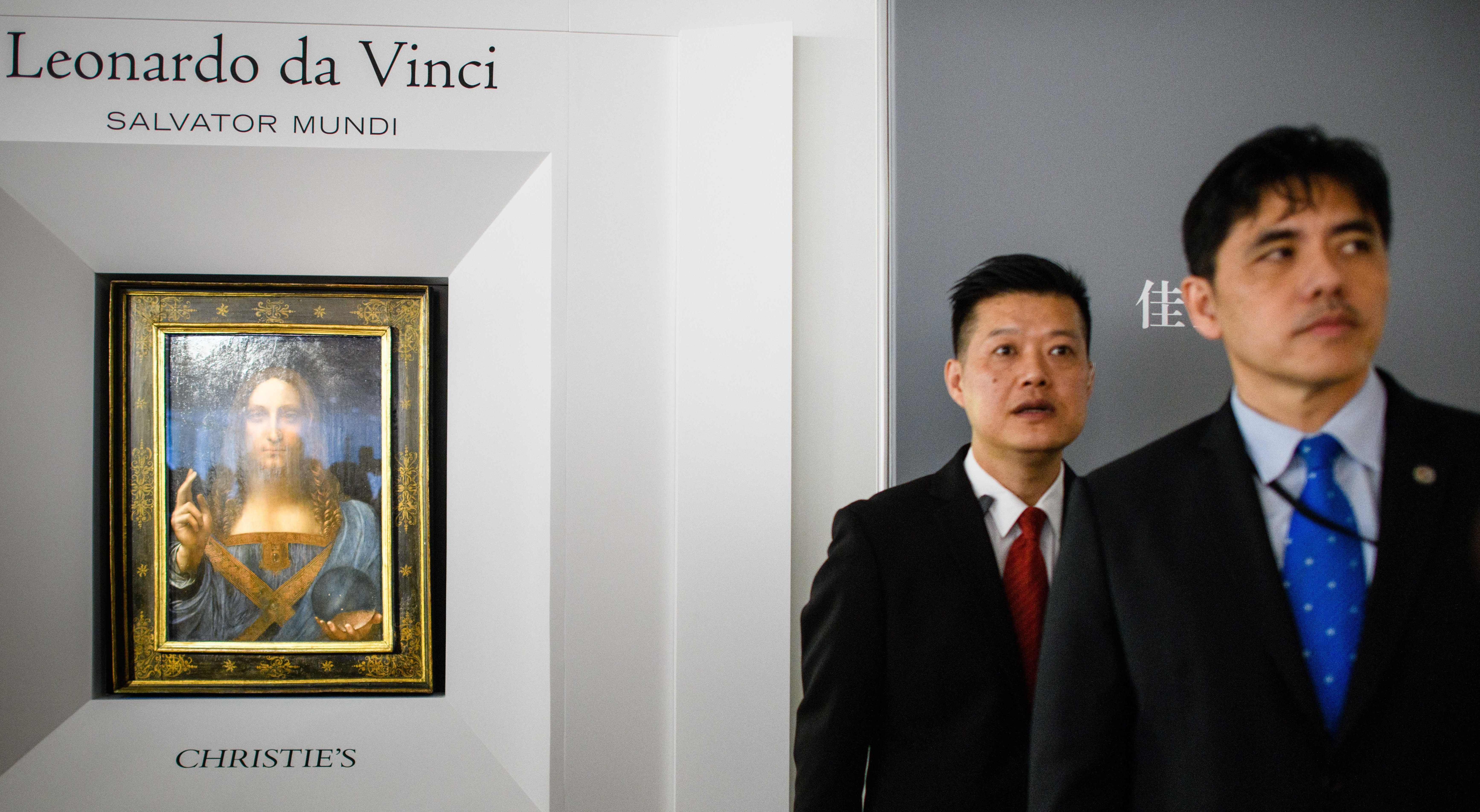 The Hong Kong media identified the man on the right as former CIA officer Jerry Chun Shing Lee. He was a security official at the unveiling of Leonardo da Vinci's <em>Salvator Mundi</em> painting at the Christie's showroom in Hong Kong on Oct. 13, 2017. Three months later, Lee was arrested at JFK airport in New York. He pleaded guilty in U.S. federal court Wednesday to spying for China. (AFP/Getty Images)