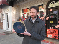 Kyle Kessler holds a pressing of Fiddlin' John Carson's "The Little Old Log Cabin in the Lane," which was recorded at 152 Nassau Street in Atlanta.