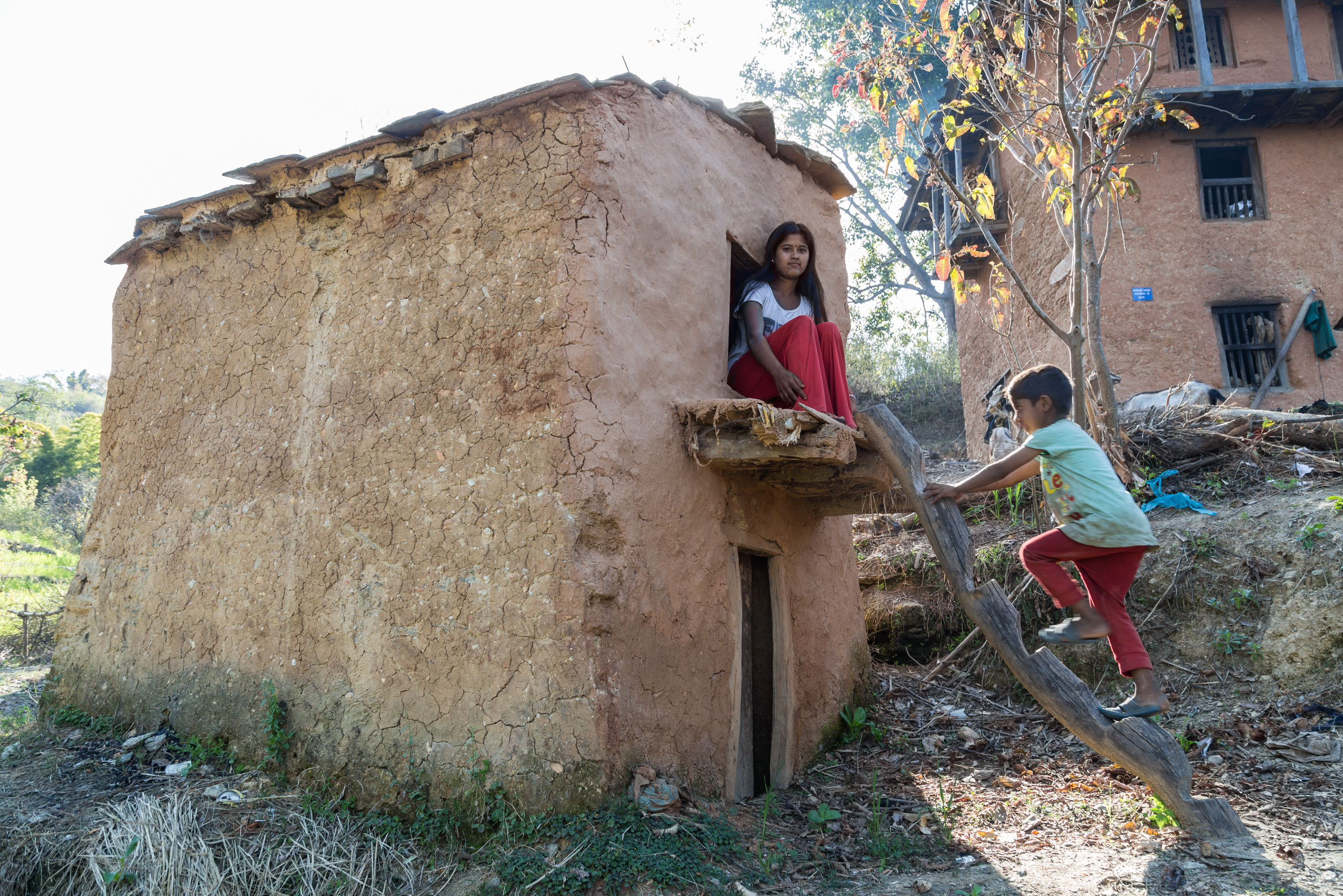 Manisha Jaisi, 16, poses at the shed outside her house where she sleeps when she has her period. Jaisi got her period two months after her neighbor, Dambara Upadhyay, died of unknown causes while sleeping in a similar shed in 2016. Jaisi says she never goes without her phone in the shed because she's scared after Upadhyay's death. (Sajana Shrestha for NPR)