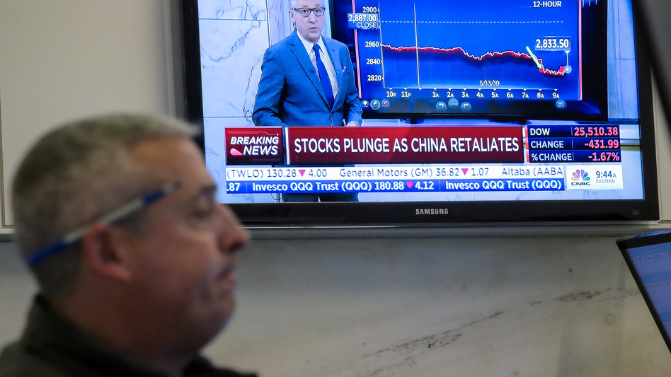 U.S. stocks fell sharply Monday after China retaliated for President Trump's latest round of tariffs. Here, a trader works on the floor at the New York Stock Exchange as a TV shows the state of the market. (Brendan McDermid/Reuters)