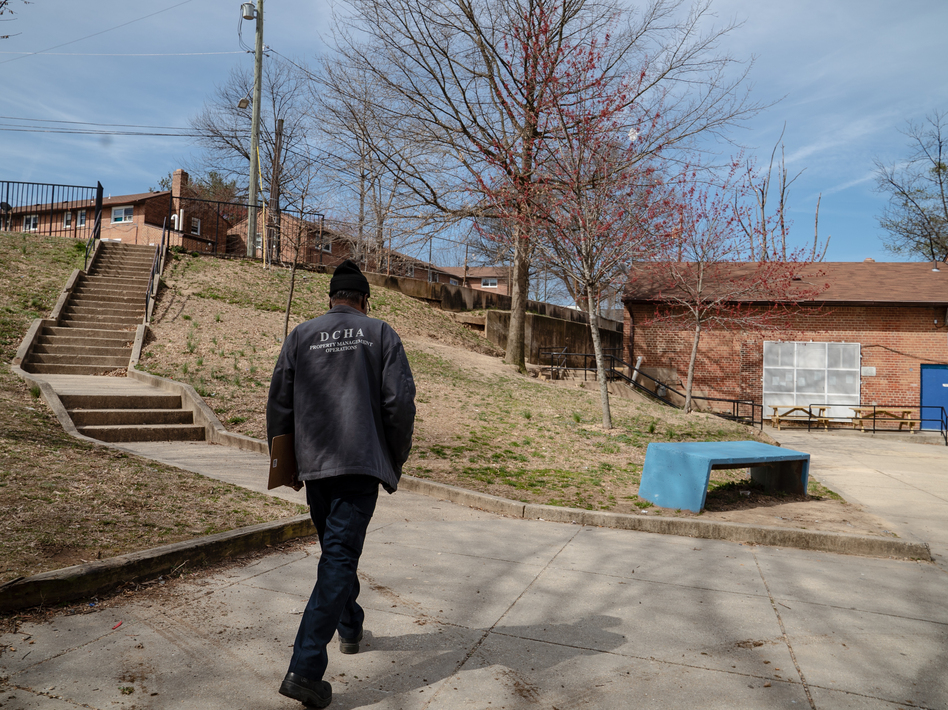 An employee of the District of Columbia Housing Authority walks on the grounds of a public housing complex called Richardson Dwellings in Northeast Washington, D.C. The Trump administration wants to eliminate the federal fund now used to repair public housing in favor of attracting more private investment to repair and replace it.