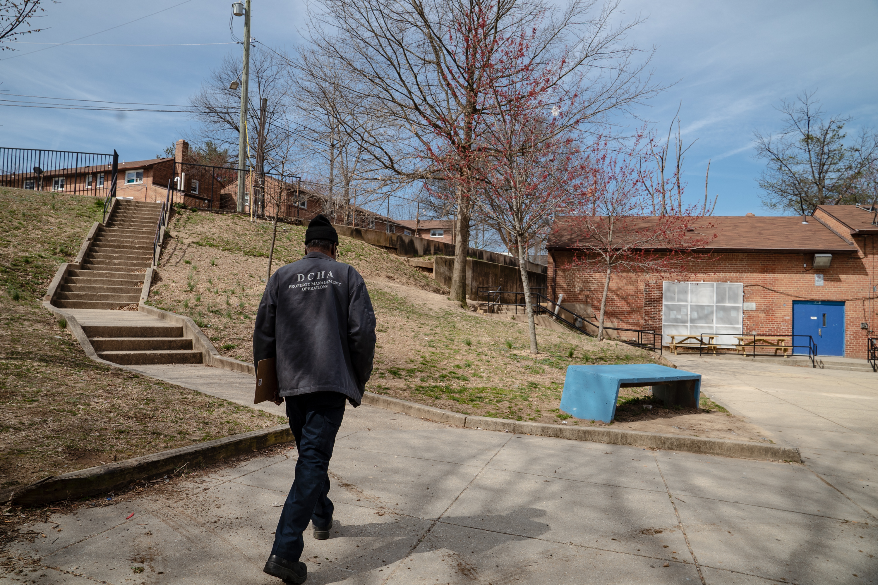 An employee of the District of Columbia Housing Authority walks on the grounds of a public housing complex called Richardson Dwellings in Northeast Washington, D.C. The Trump administration wants to eliminate the federal fund now used to repair public housing in favor of attracting more private investment to repair and replace it. (Amr Alfiky/NPR)