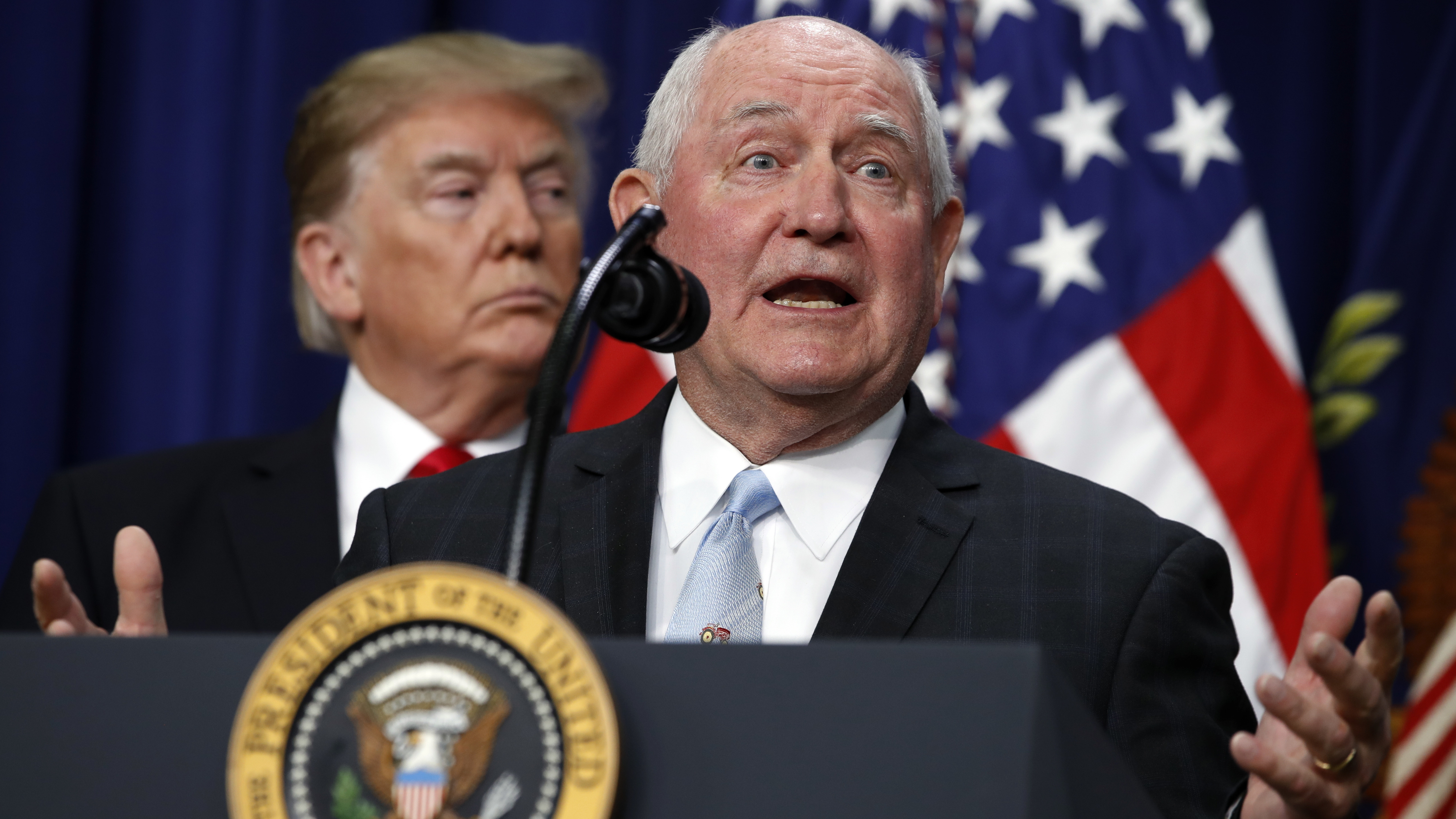 President Trump listens to Agriculture Secretary Sonny Perdue during a signing ceremony. The USDA wants to move two vital research agencies out of Washington D.C.