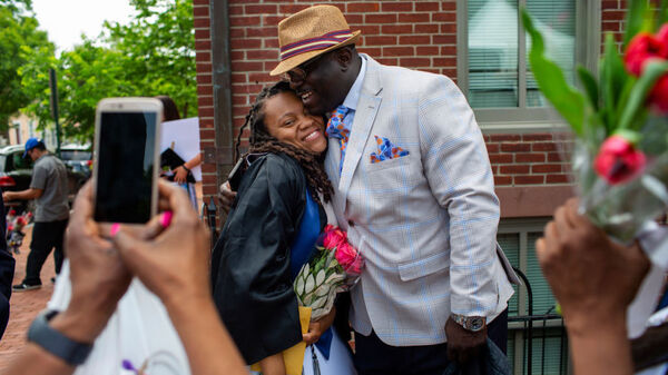 Rashema Melson gets a hug and has her photo taken with her cousin Anthony Young after the 2019 Georgetown University graduation ceremony.