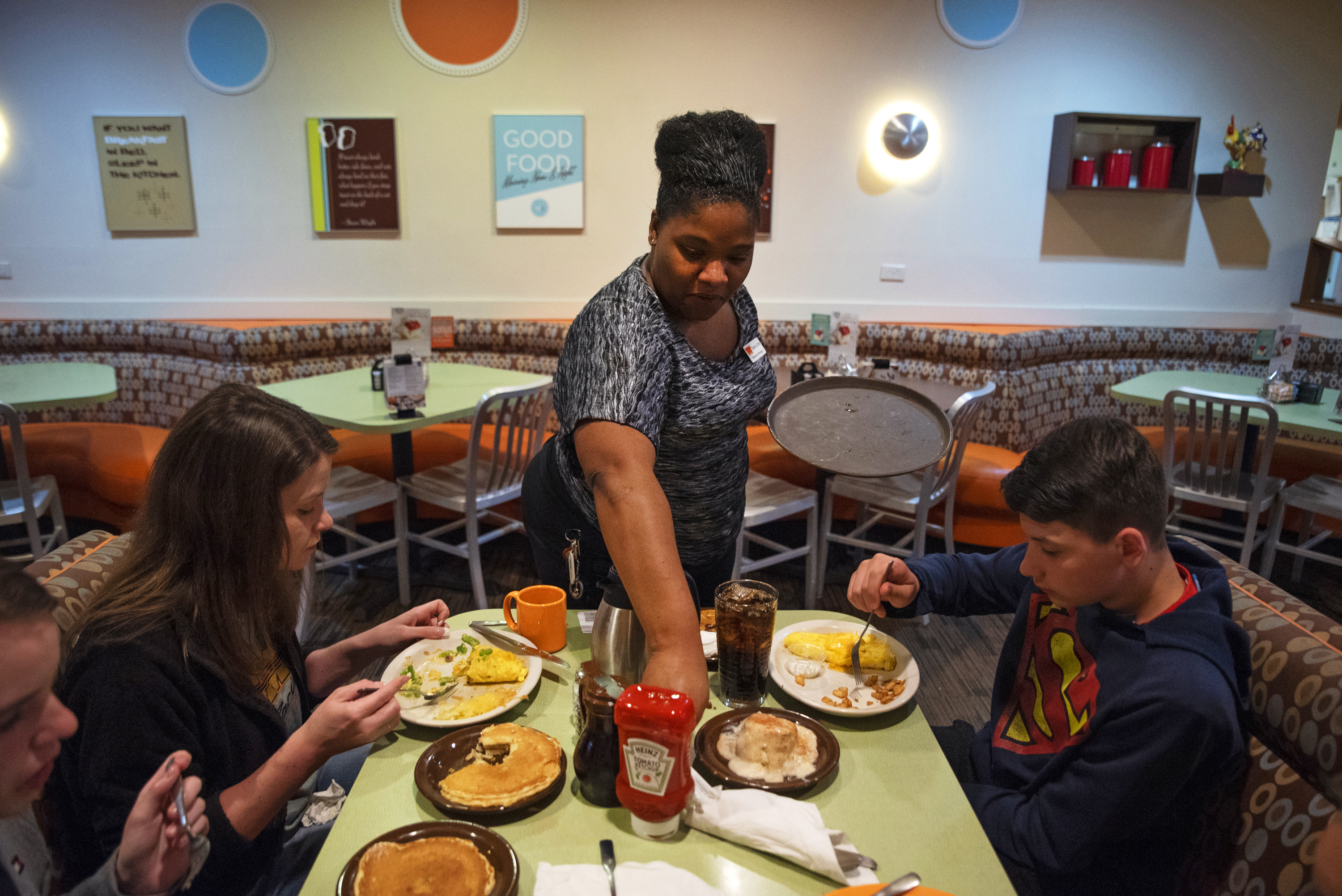 Tanisha Cortez waits on a table at a restaurant in Ames, Iowa. When the previous restaurant she worked for closed, Cortez applied to others and had job offers right away. Jobs are plentiful in Ames, a small city of more than 65,000 residents tucked amid farm fields north of Des Moines. (Olivia Sun for NPR)