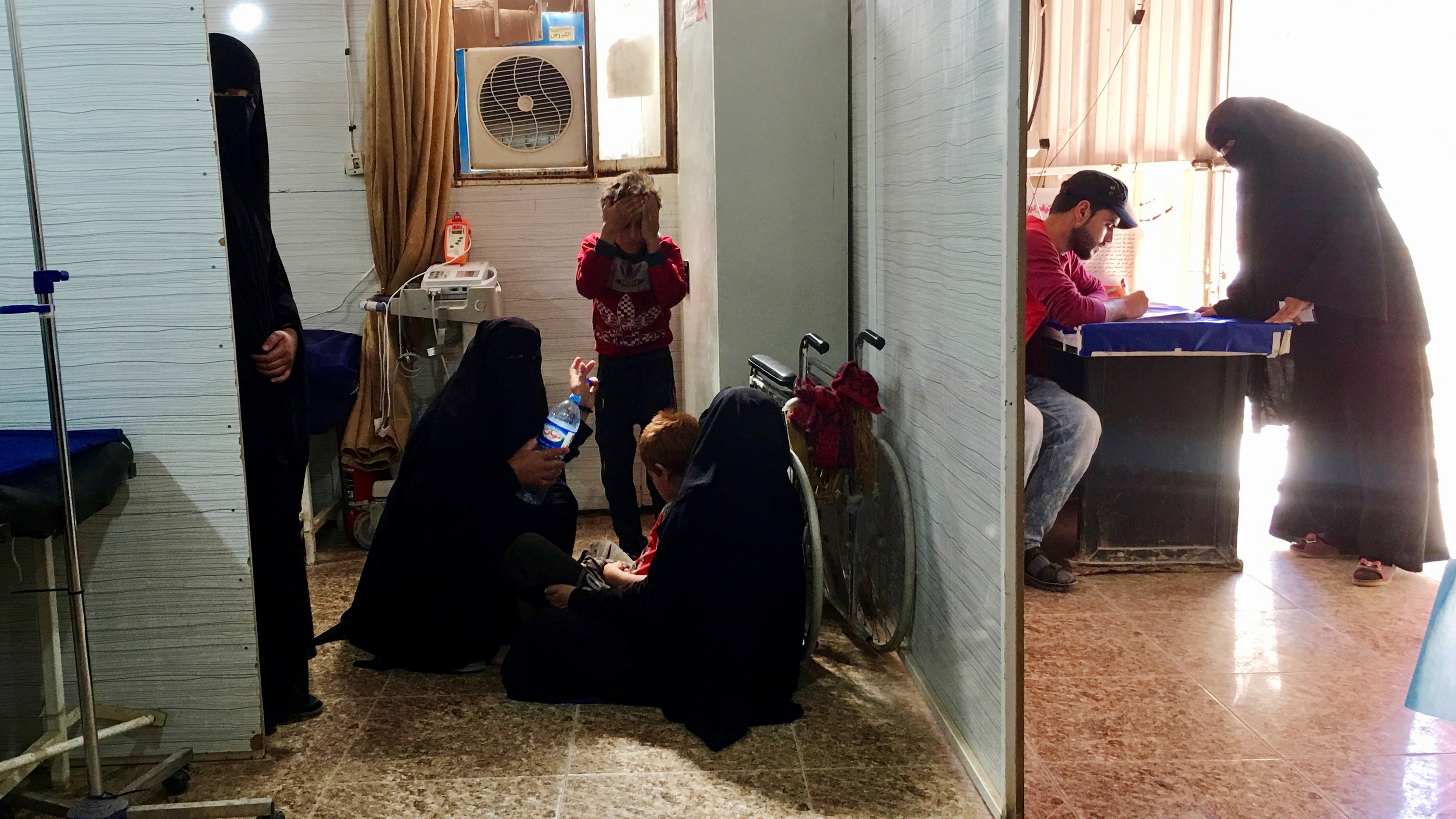 Women sit on the floor as they wait in a clinic at the al-Hol detention camp.